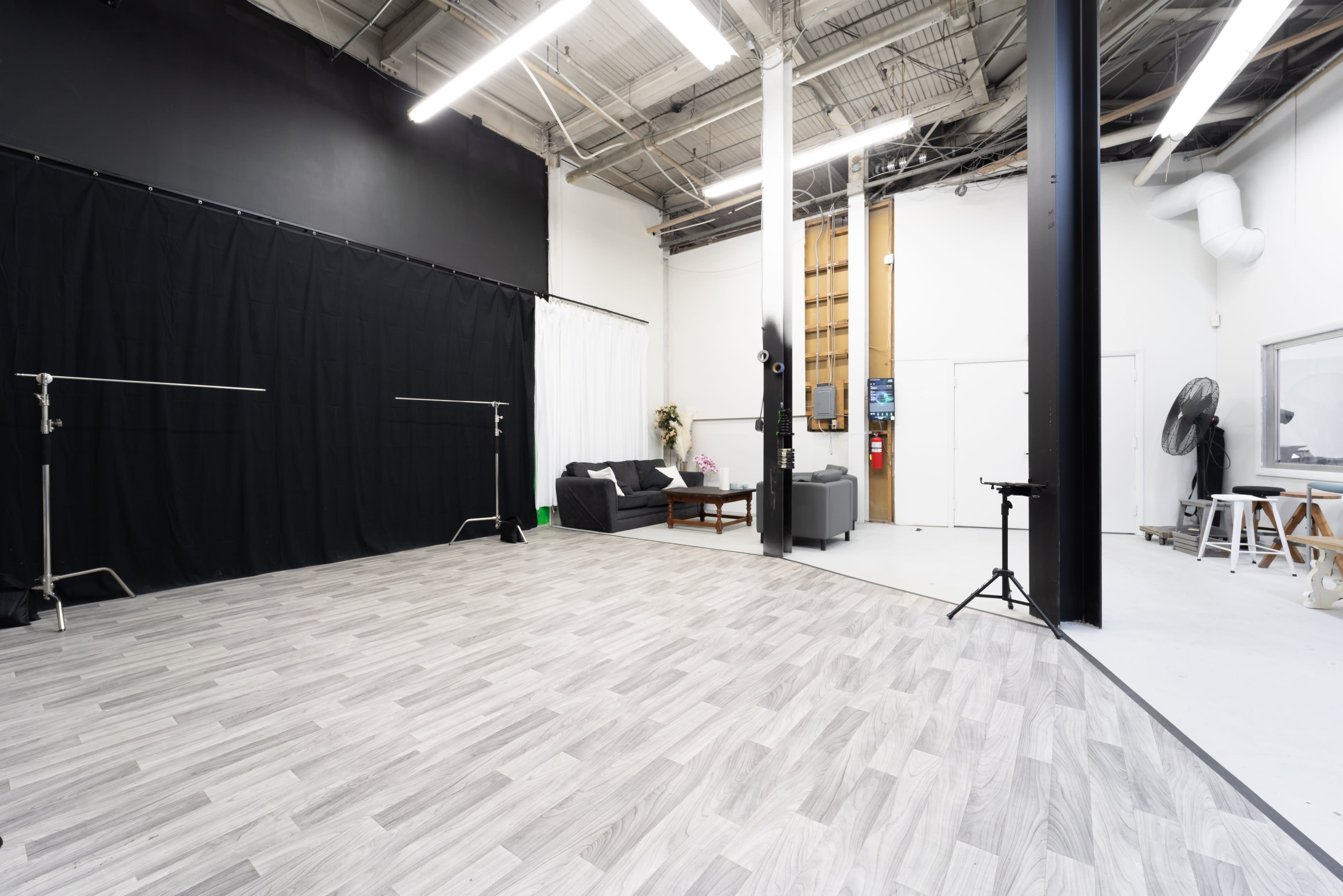 A person sitting on a stool in a studio is reaching out with their arms during a video shoot.