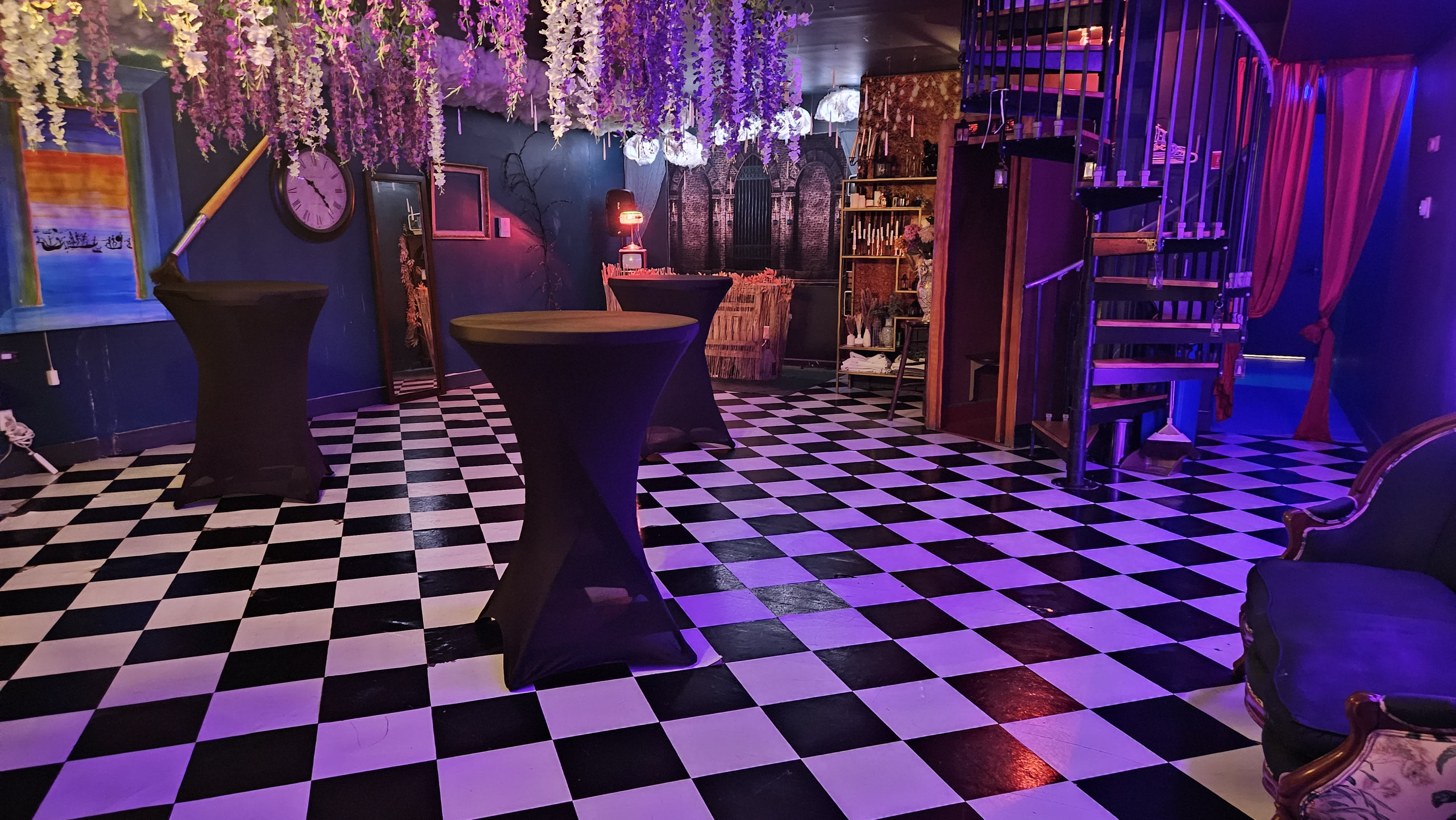 Four individuals dressed in creative costumes pose together at a birthday party, with a vintage sofa and neon lights in the background.