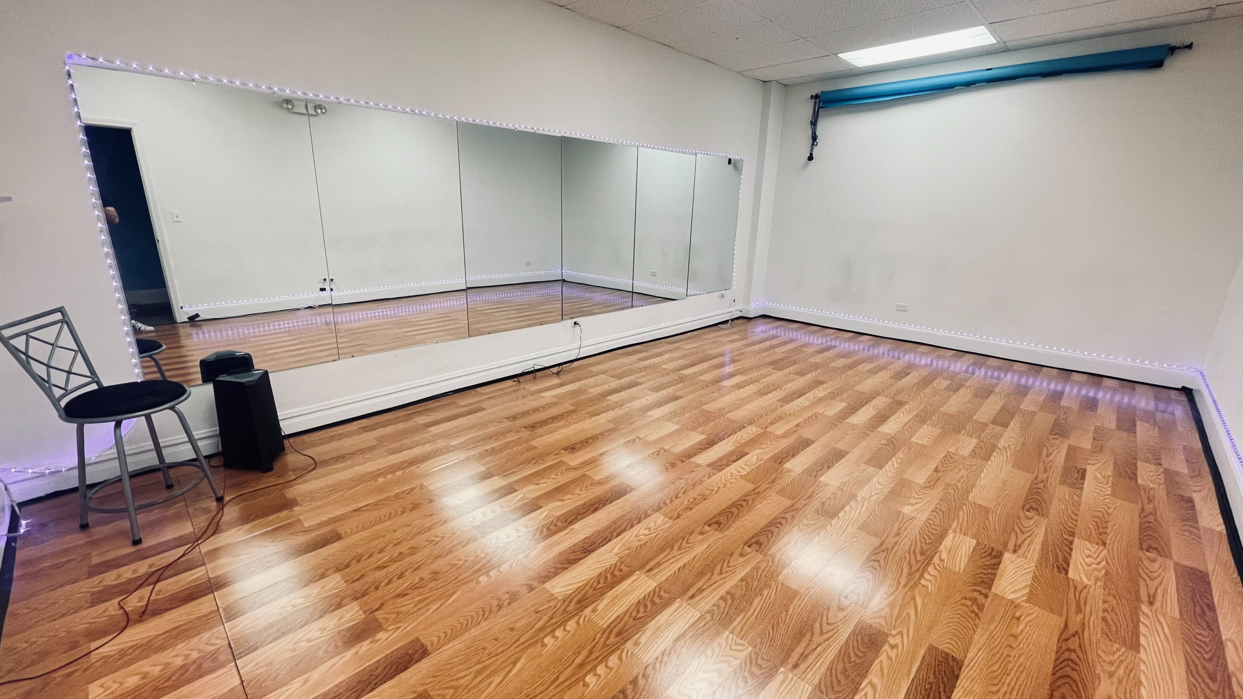 Two dancers are rehearsing choreography in a mirrored studio with wooden floors and soft lighting.