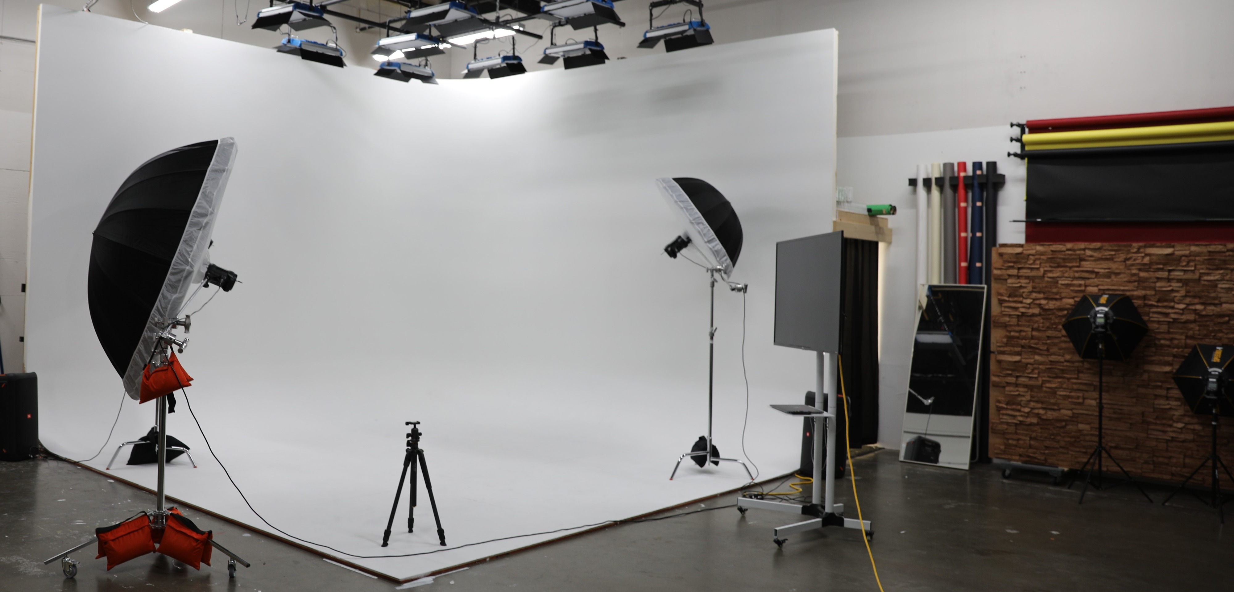 A group of six individuals poses for a photoshoot, each holding books and engaging with the camera in a studio setting.