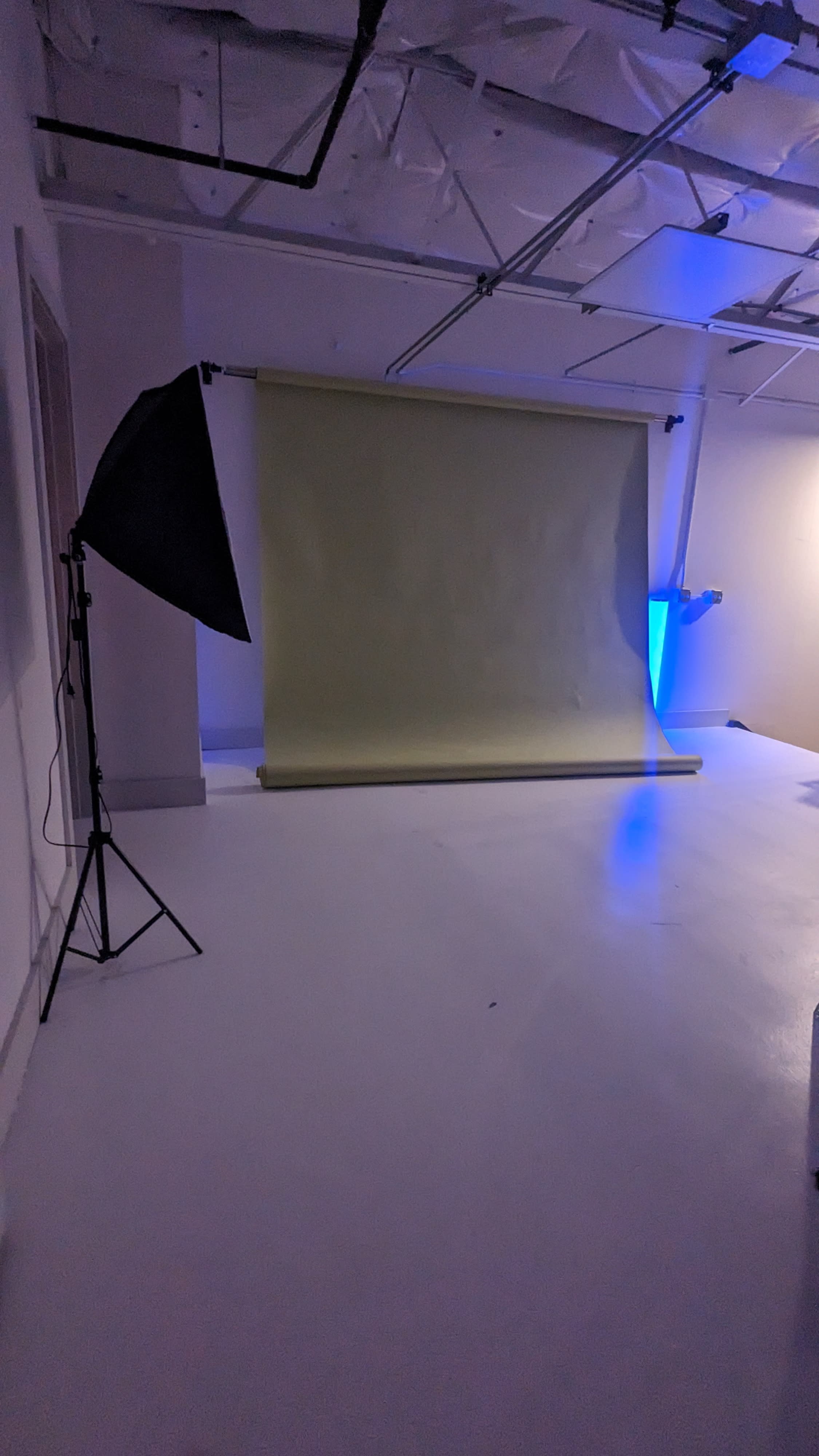 A woman sits on the floor with two children, posing together in a bright, minimalistic studio.