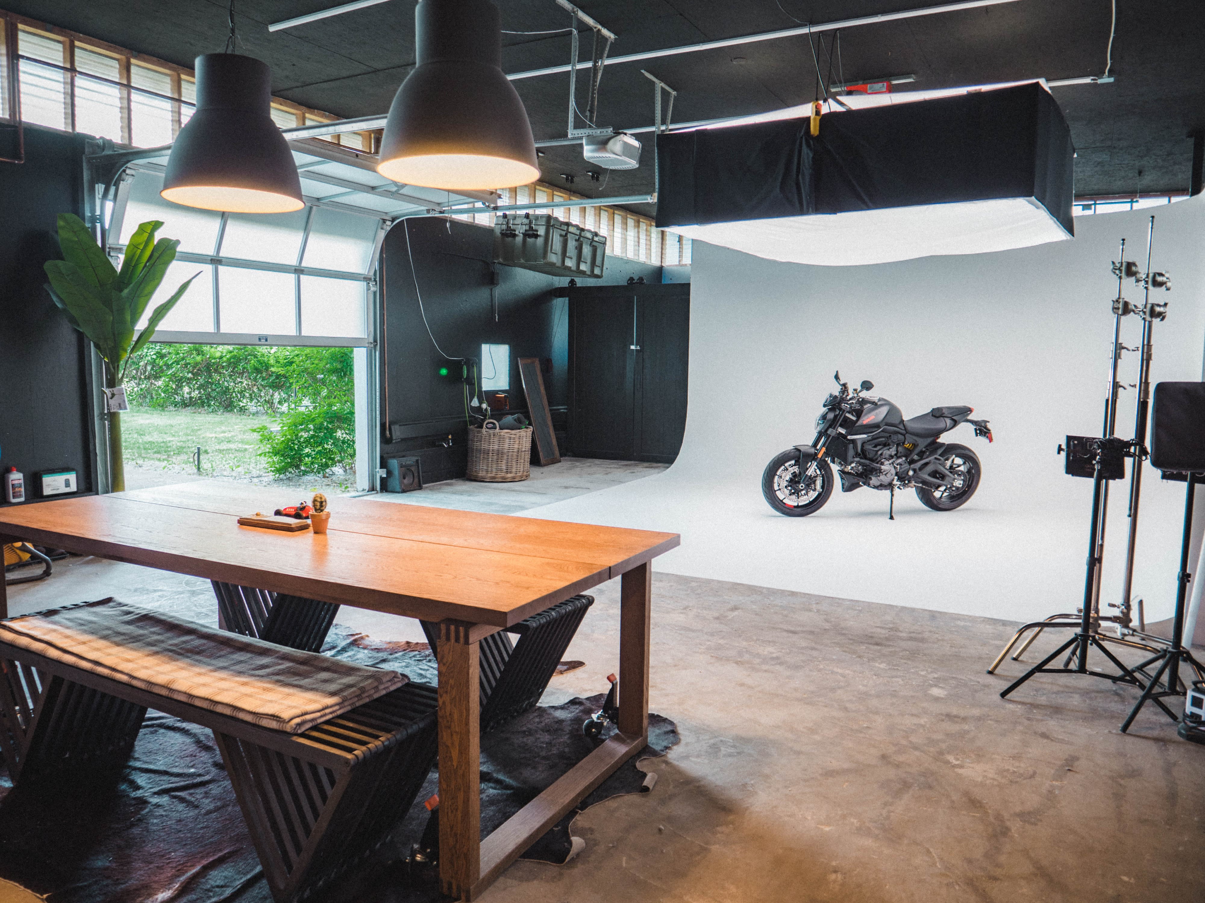 A photographer captures images of a model posing in a studio setting with a plain white background.