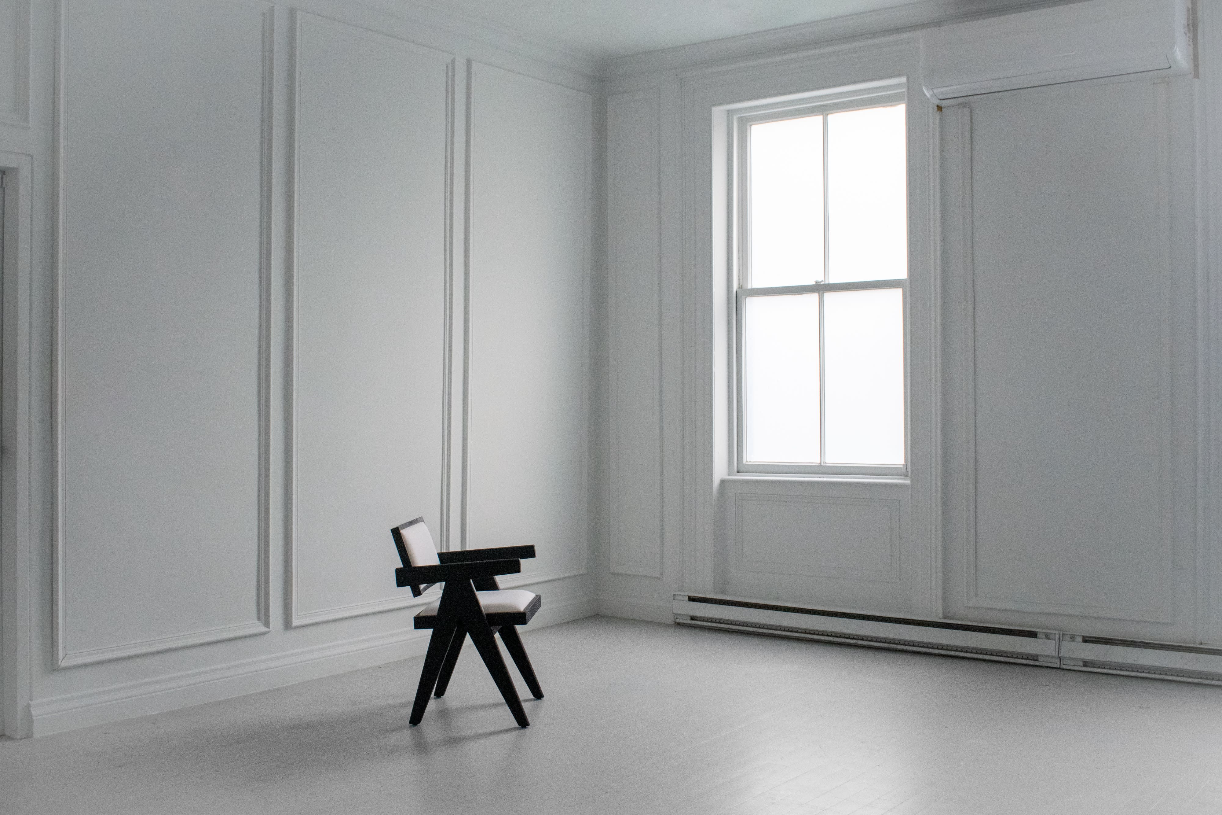Two women are posing on a gray couch in a stylish room with large windows, showcasing dynamic and creative body positions.