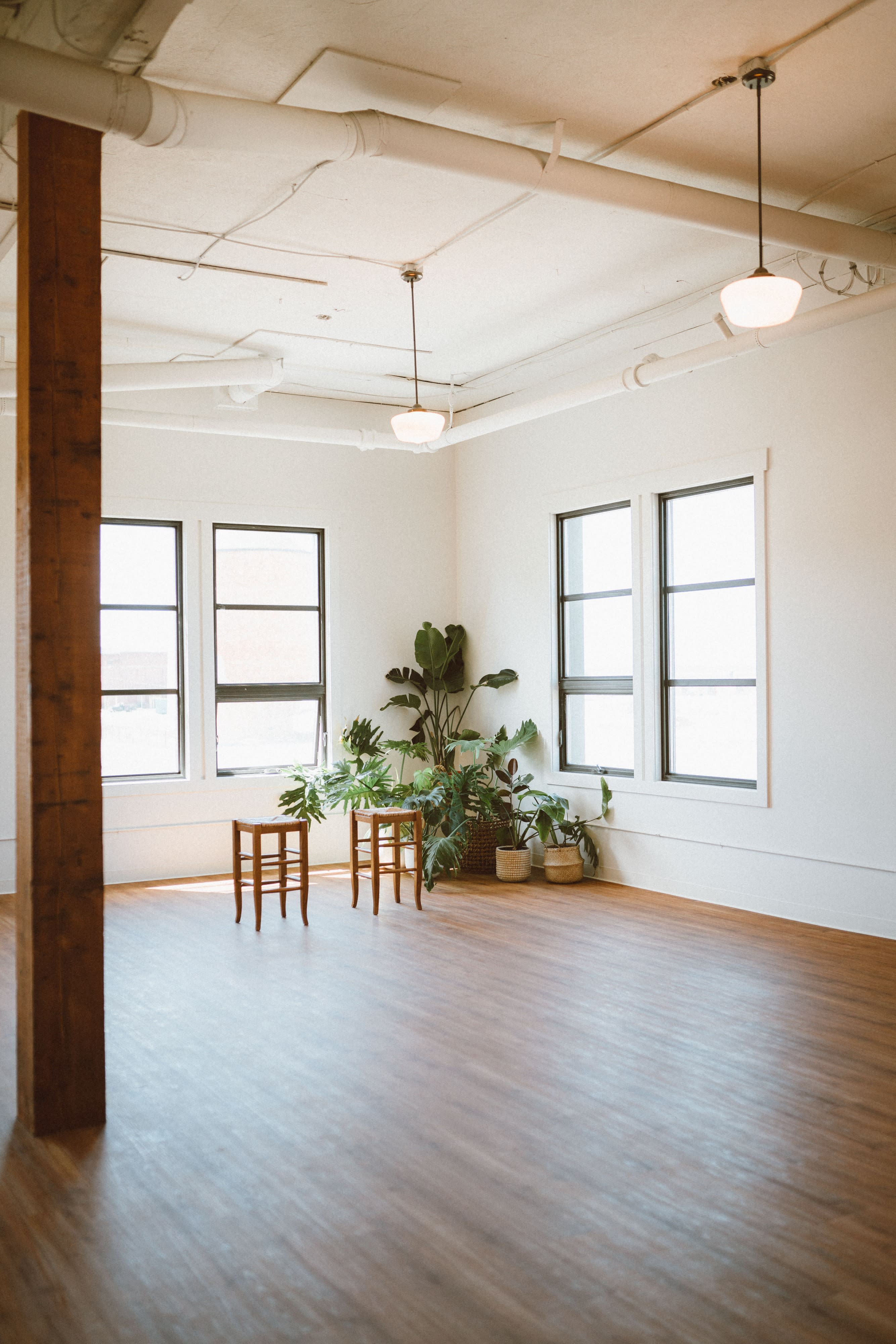 A couple sits on the floor in a bright, empty room, sharing an intimate moment together.