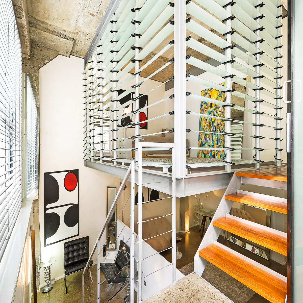 The scene shows three tripods set up in a living space, with cameras and gear placed on a white couch and nearby floor.