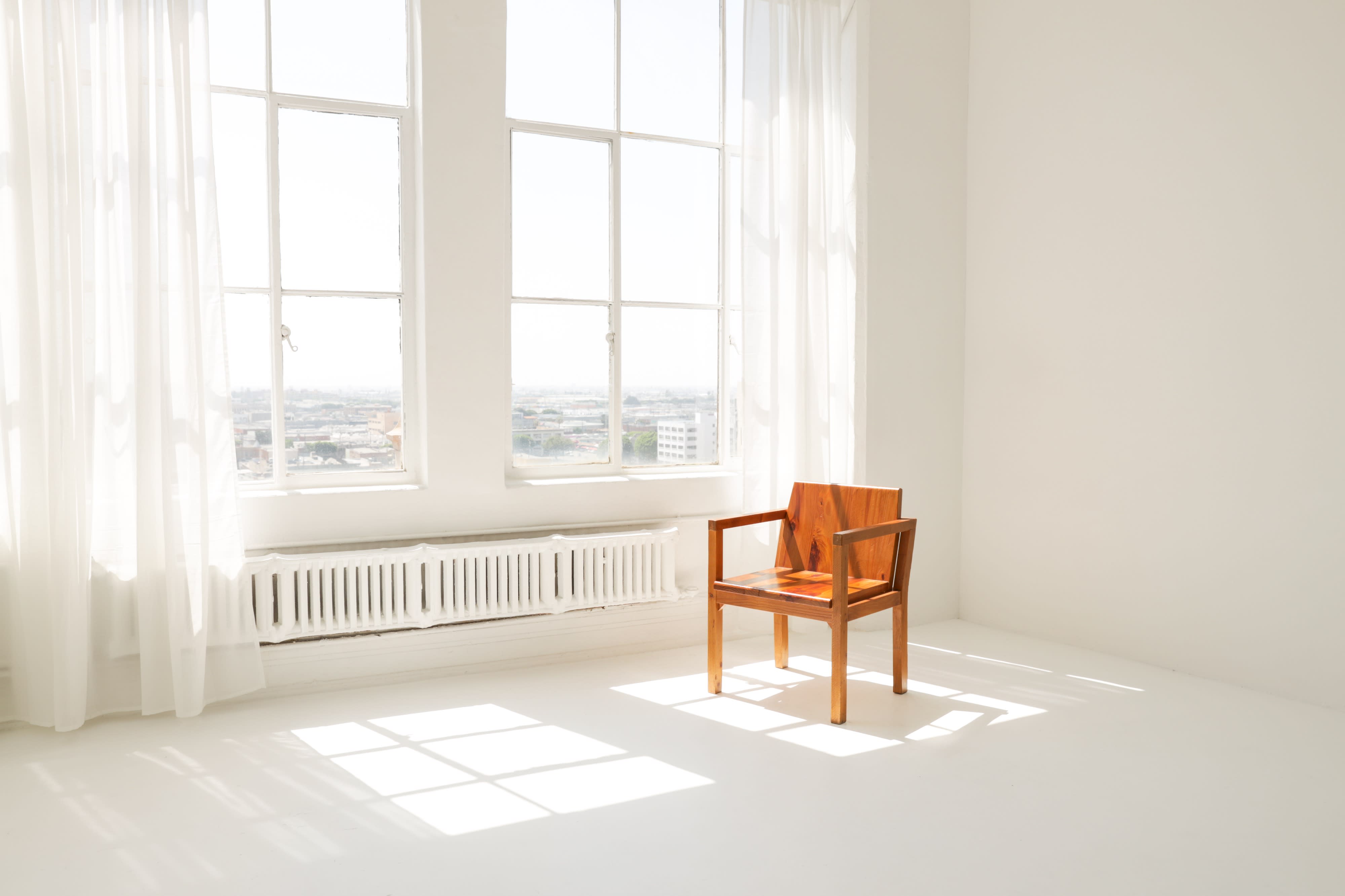 A spacious, well-lit room with large windows offers a backdrop for a video shoot, featuring a view of the sunset over the city.