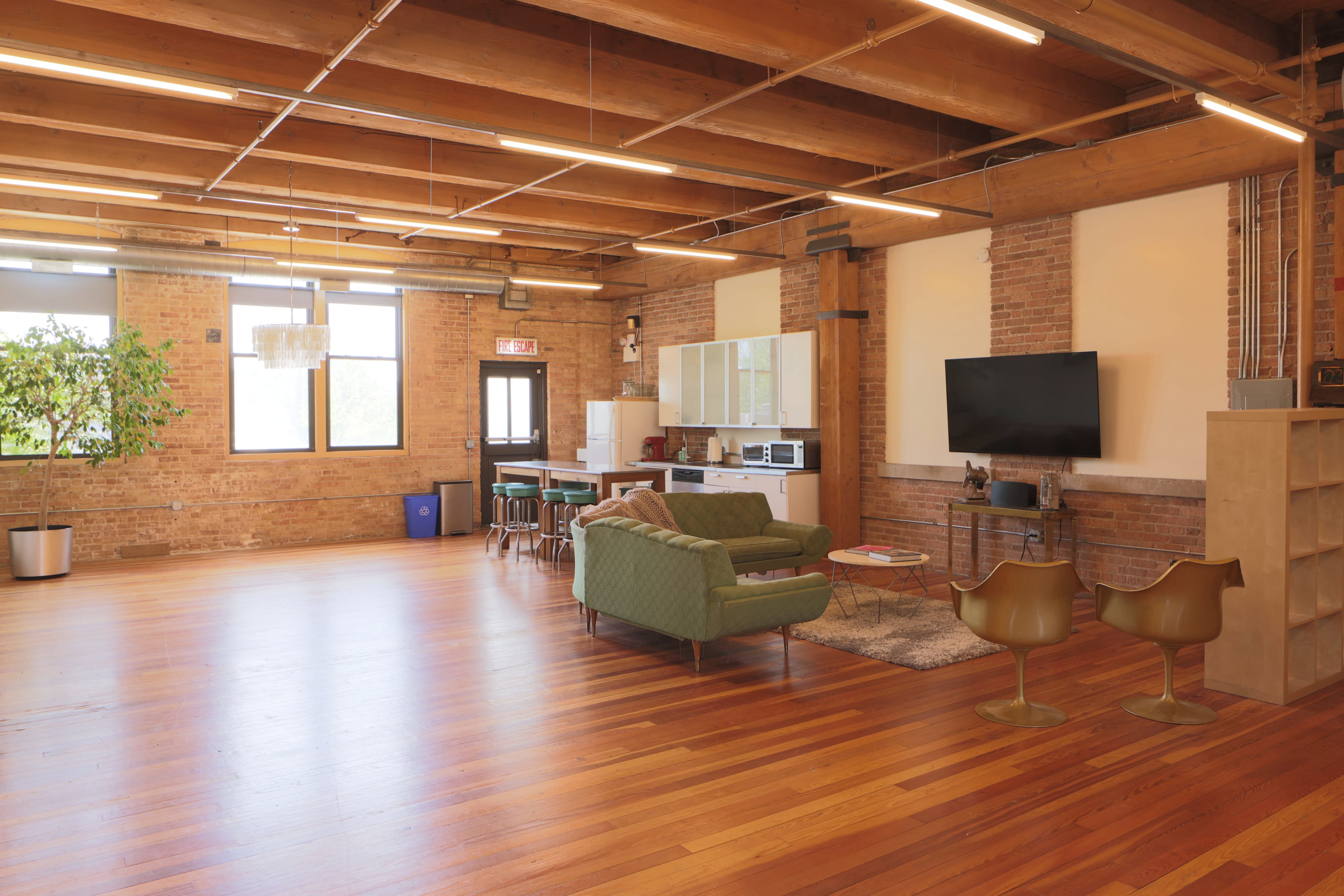 A spacious office with wooden floors and large windows features a video interview setup, including a sleek desk and seating area.
