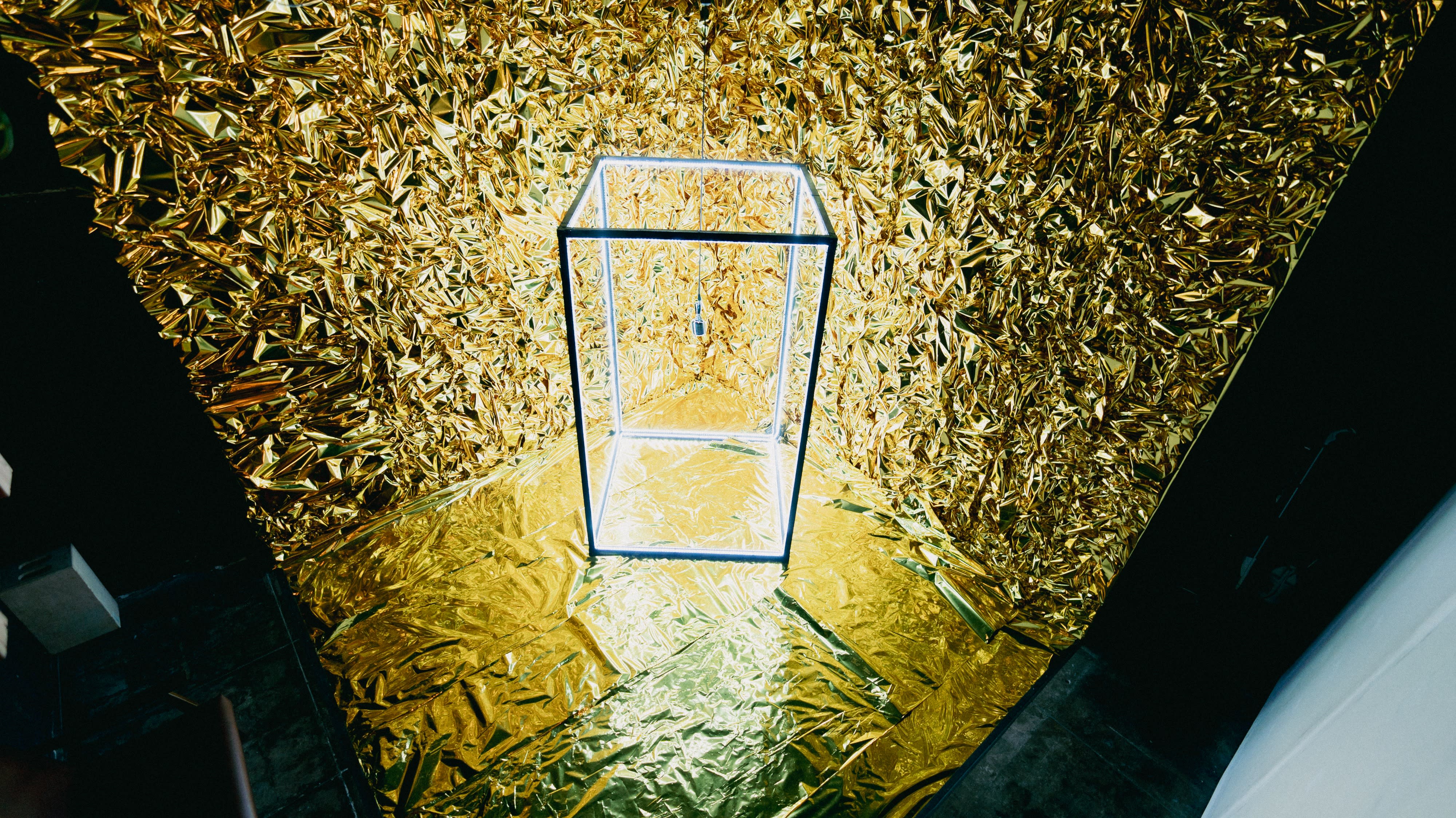A man stands inside a lighted frame while preparing for a video shoot with a camera positioned nearby.