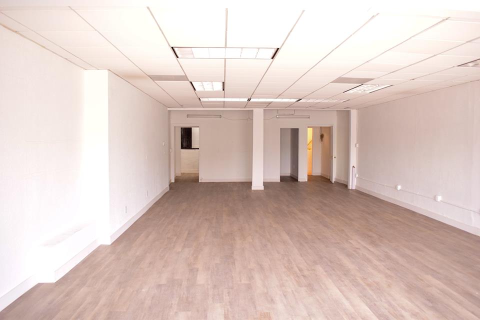 Two individuals engage in conversation at an art gallery while another person works on the floor.