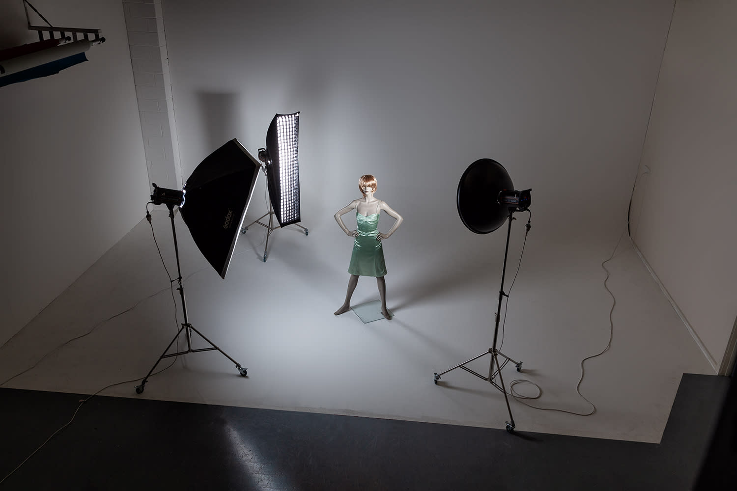 A person in a black mask poses while another individual films them with a camera in a studio setting.