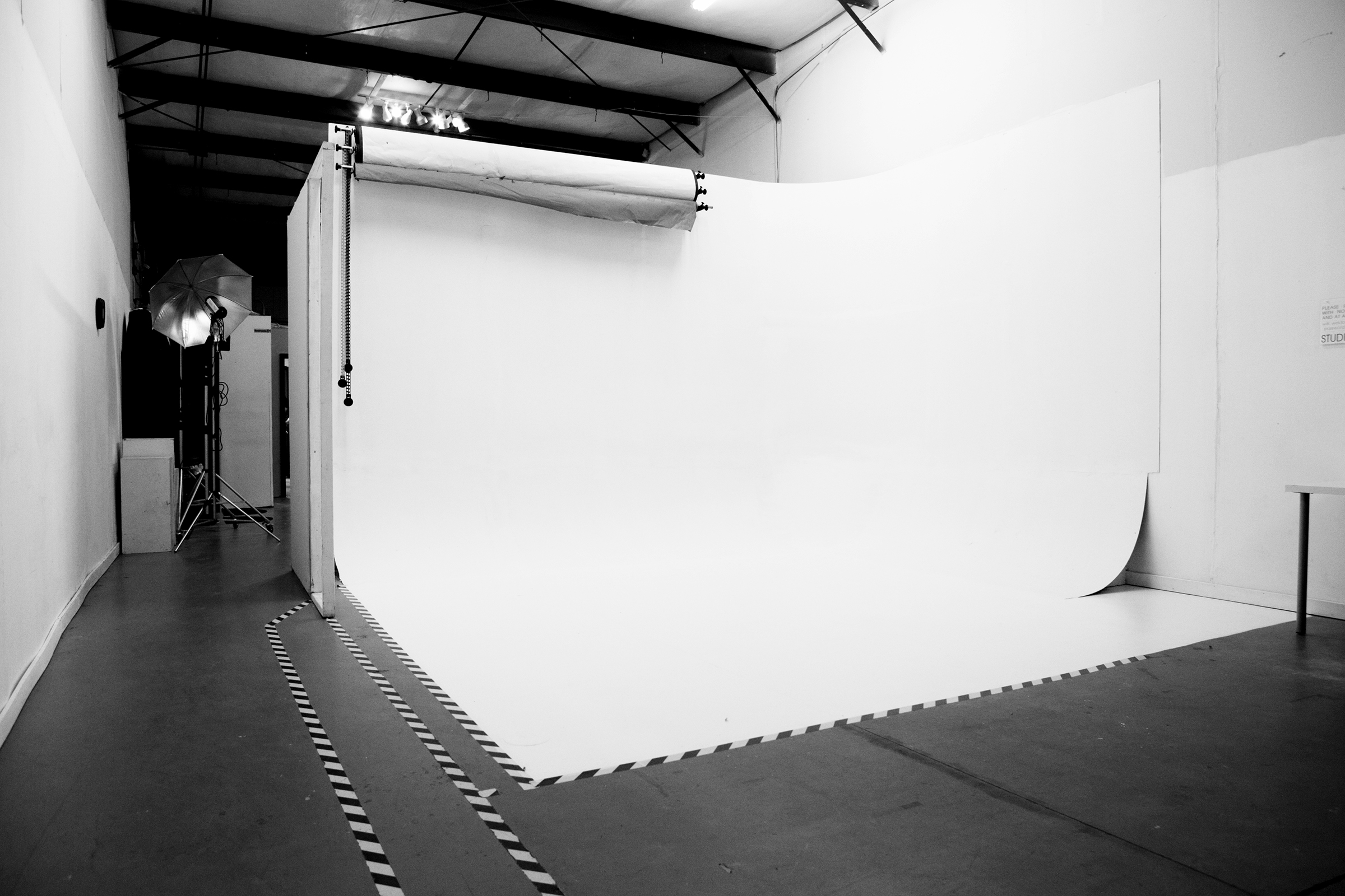 A model poses with a vintage camcorder and gestures enthusiastically while another person captures the scene with a camera in a green-lit studio setting.