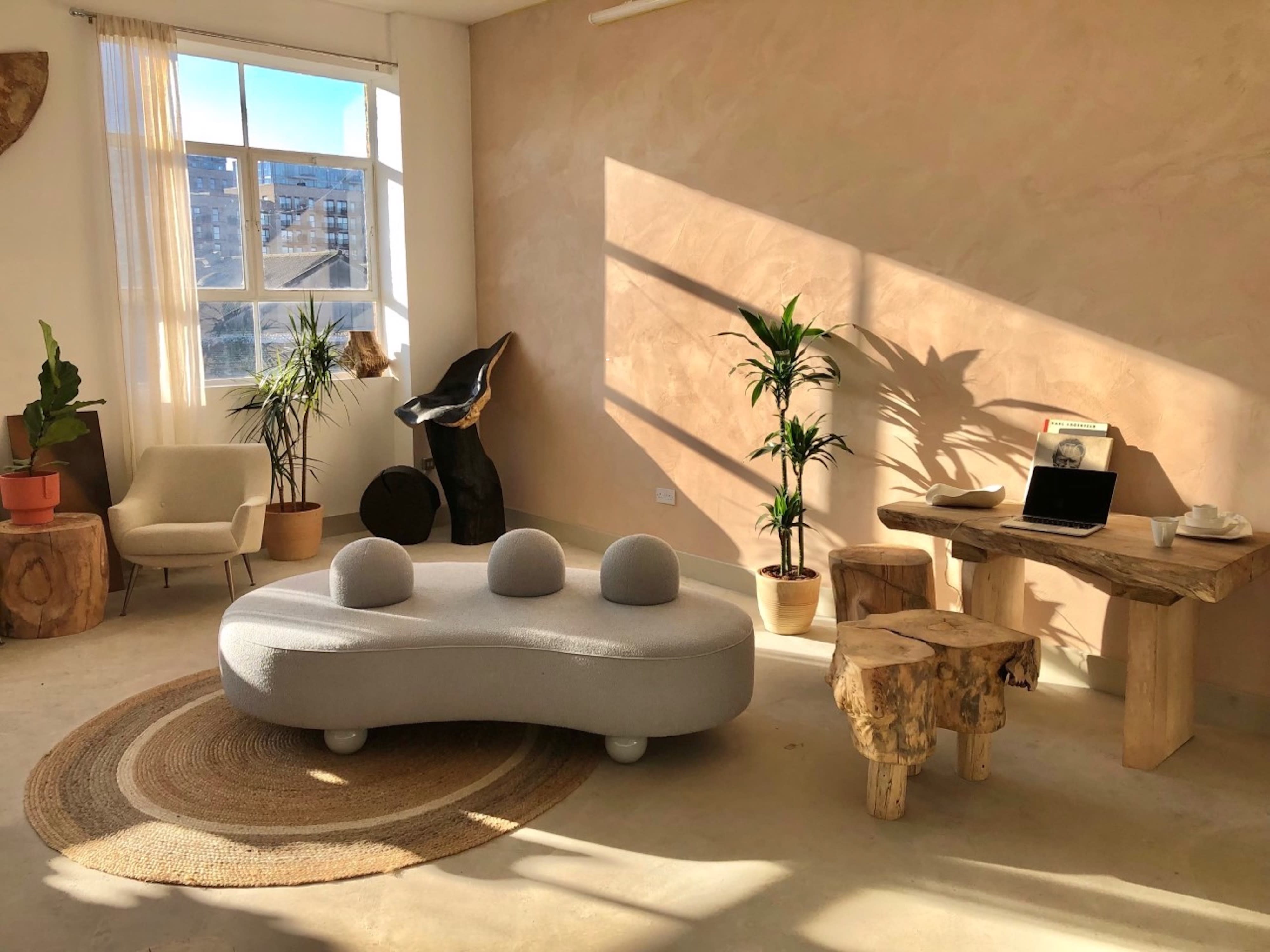 The image depicts a creatively arranged indoor space featuring wooden furniture, sculptures, and decorative elements under a structured ceiling.