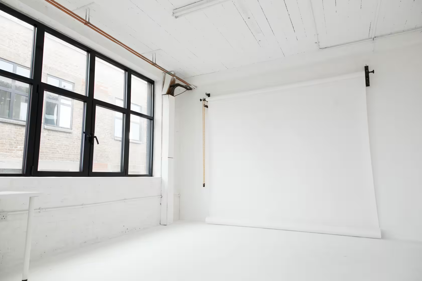 A cardboard box labeled "BALUCH" sits on a wooden stool in a studio setting with a plain white backdrop and lighting equipment positioned nearby.