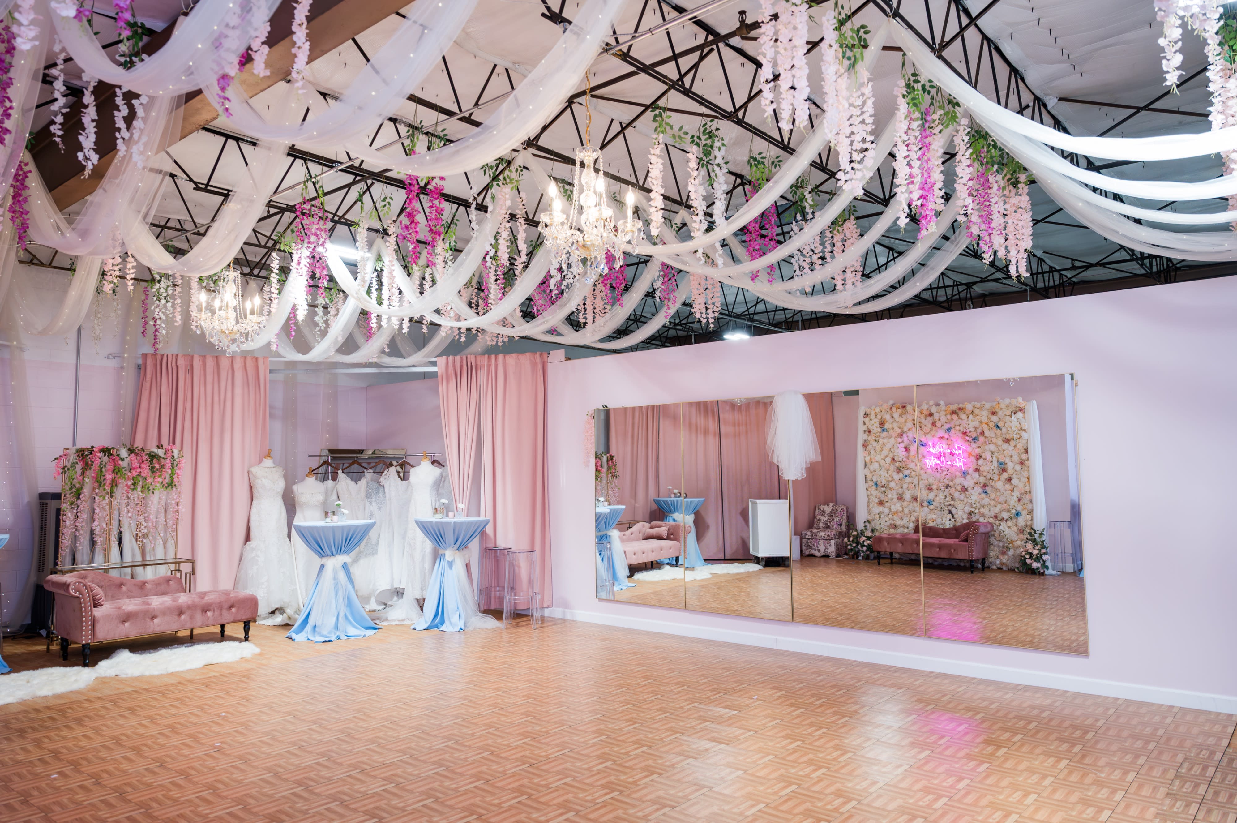 Two young women dressed in themed costumes stand together in front of a floral backdrop at a Sweet 16 celebration.