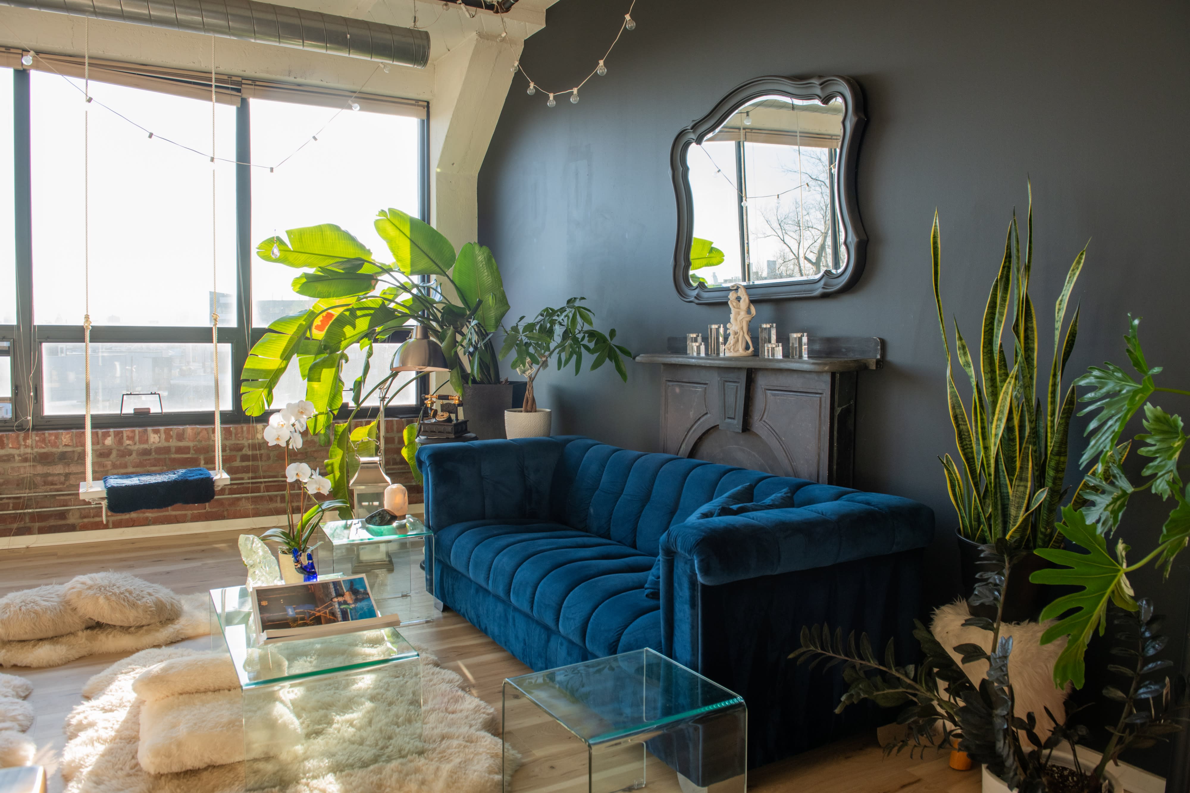A woman reviews photos on a camera while sitting on a blue sofa in a well-lit room.