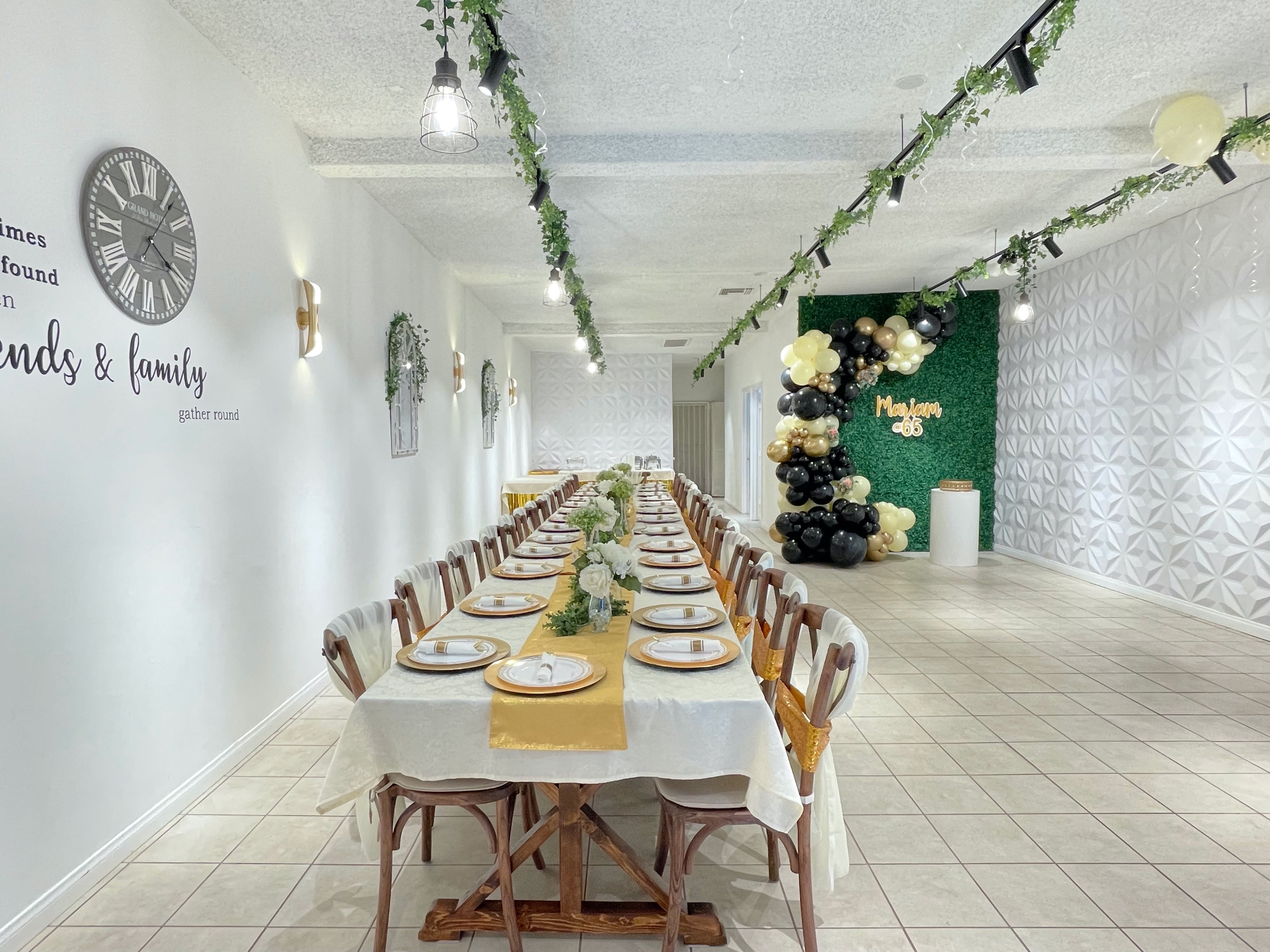 A dining table is set for a Sweet 16 celebration in a room decorated with a tree-themed backdrop.