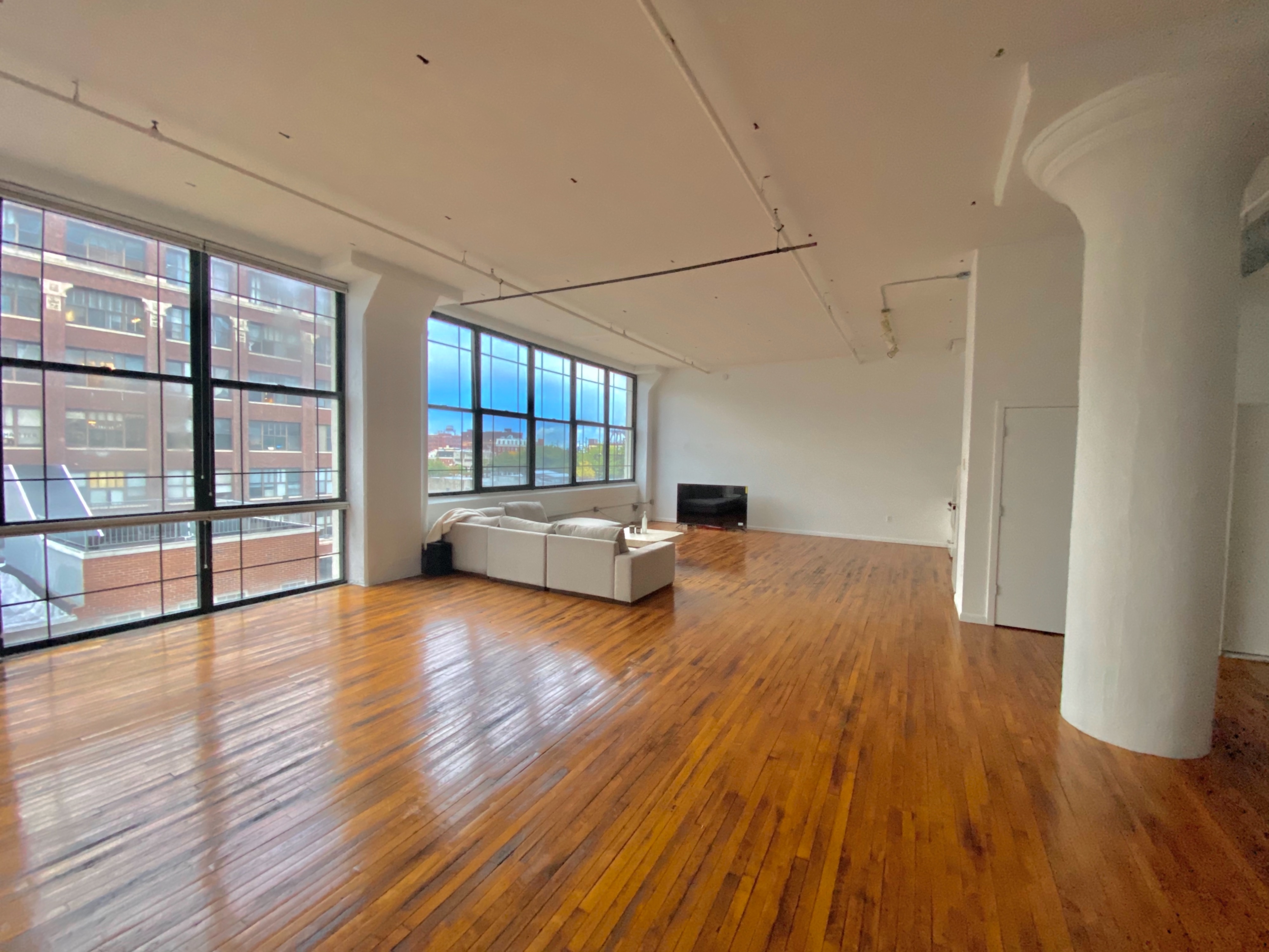 A camera is set up on a tripod, capturing a panoramic view of a spacious living room with large windows and modern furnishings.