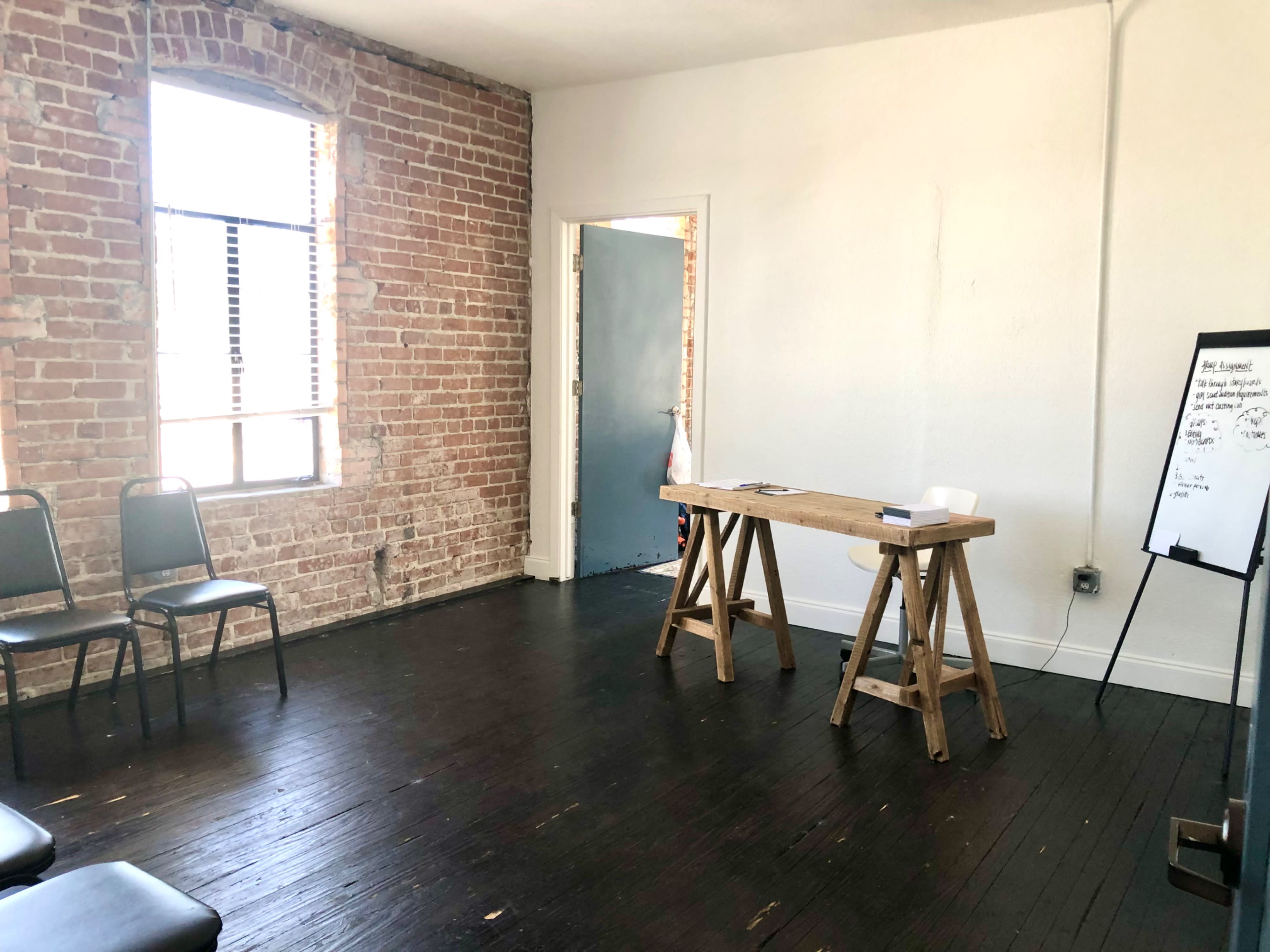 A dining table set for a meal is positioned near a window in a room with exposed brick walls and modern decor.