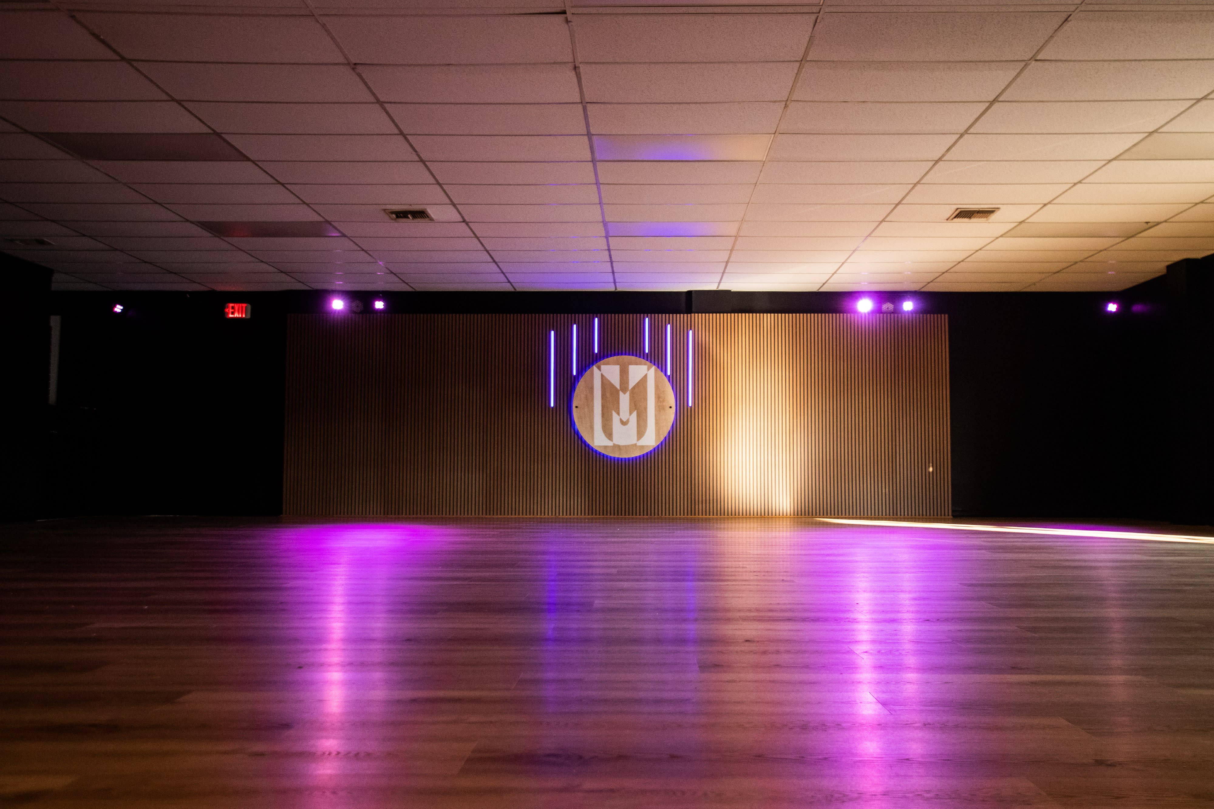 A table is set for a 16th birthday party, illuminated by neon signs and colorful lighting.