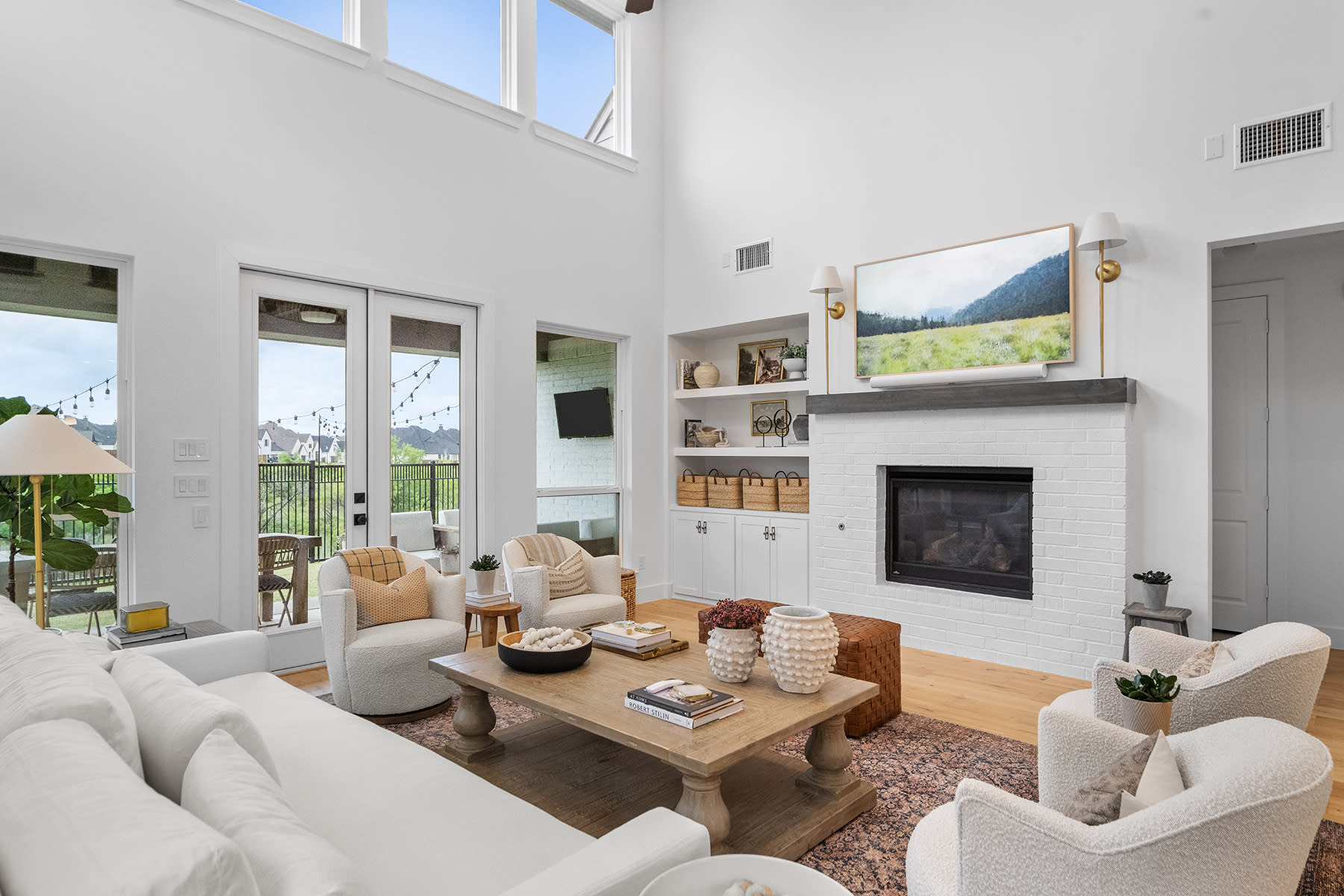 The scene shows a video shoot setup in a spacious living room, featuring a light source, camera equipment, and a minimalist seating arrangement.