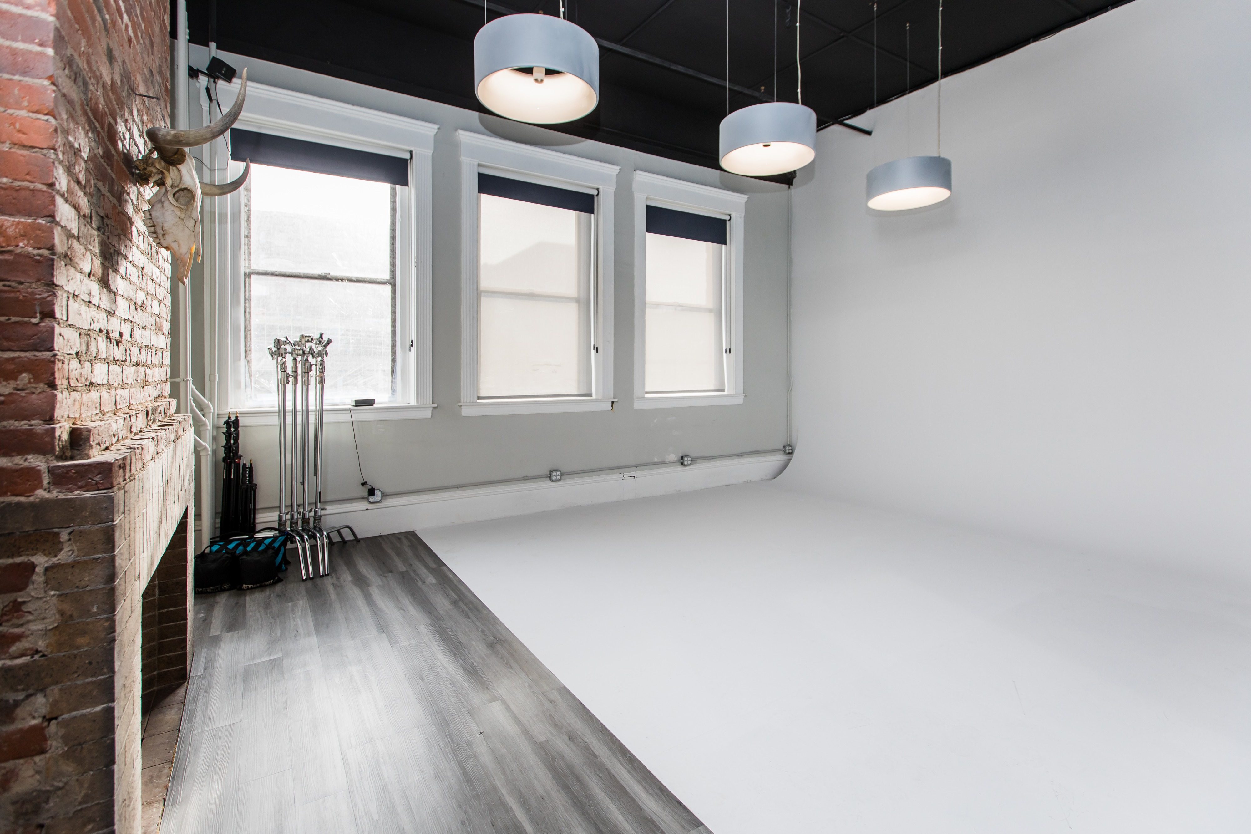 A photographer captures a model posing thoughtfully on a stool during a studio photo shoot.
