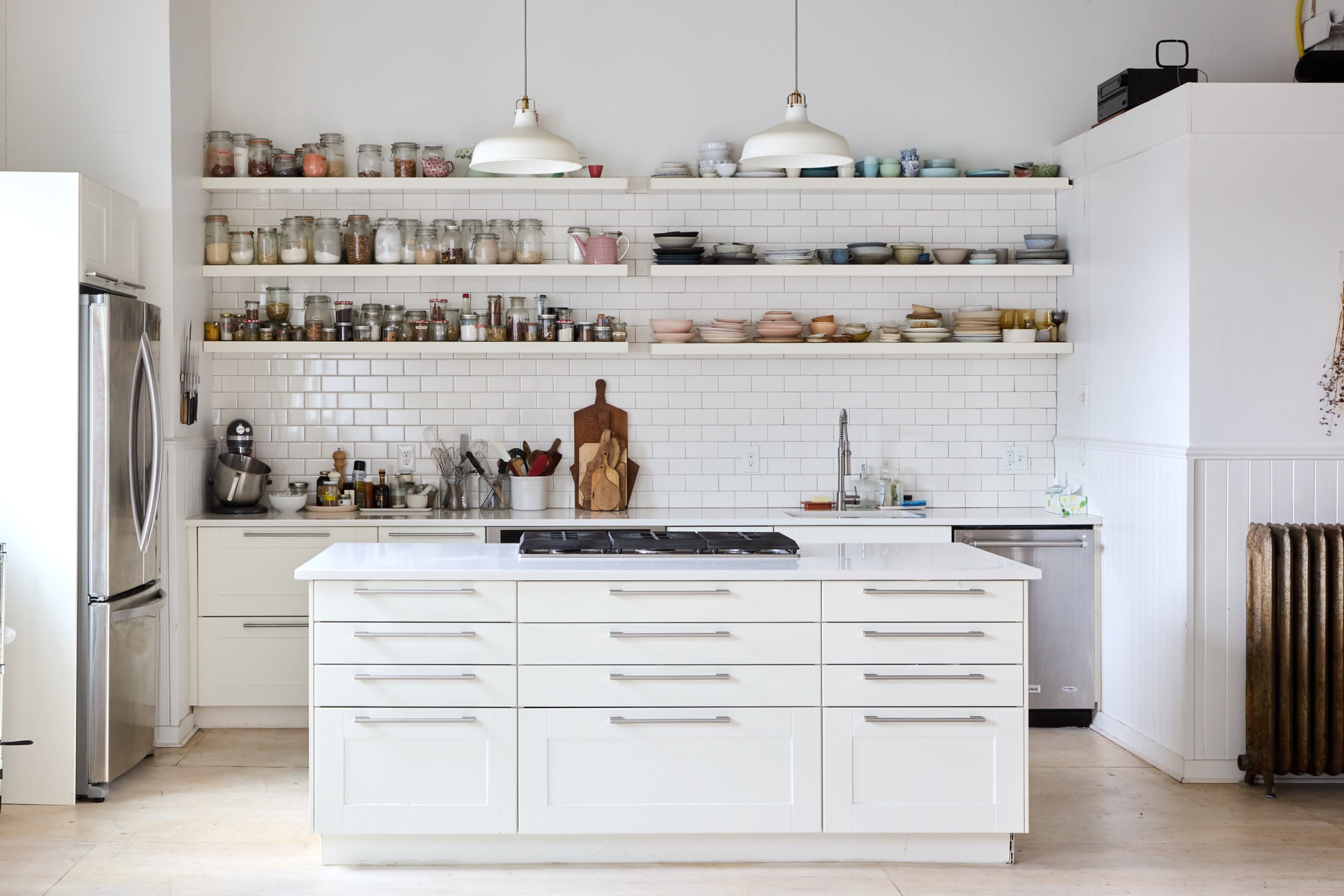 A chef is standing in a modern kitchen holding a container of organic flour while surrounded by bowls of ingredients and utensils.