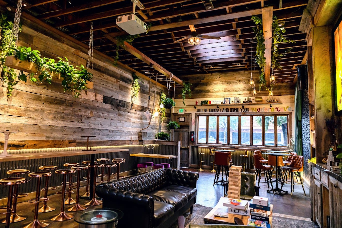 The interior of a rustic café features wood paneling, bar seating, and a window illuminated by natural light, creating a relaxed setting for patrons.