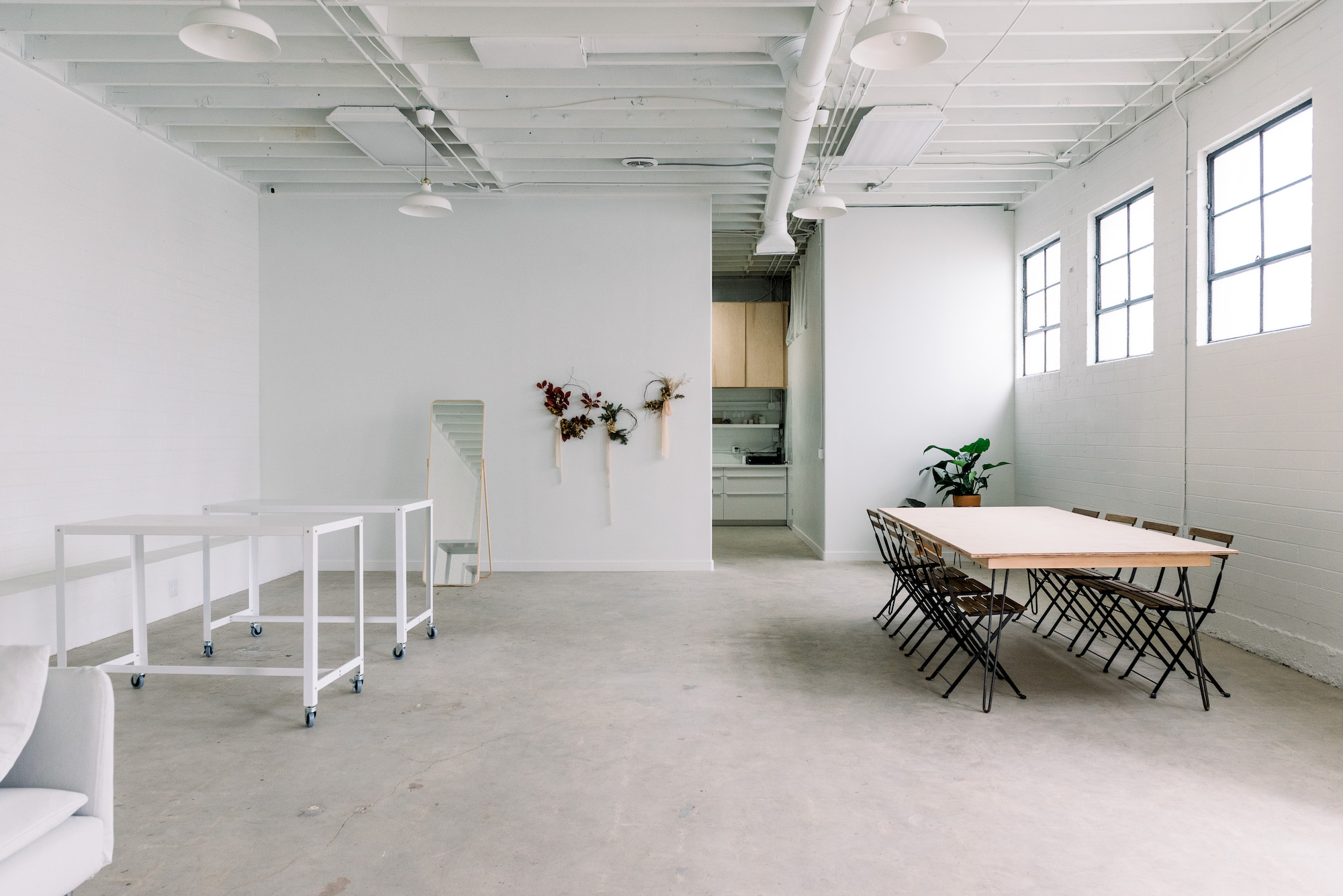 Two floral installations featuring roses and baby's breath stand on a concrete floor against a white wall.