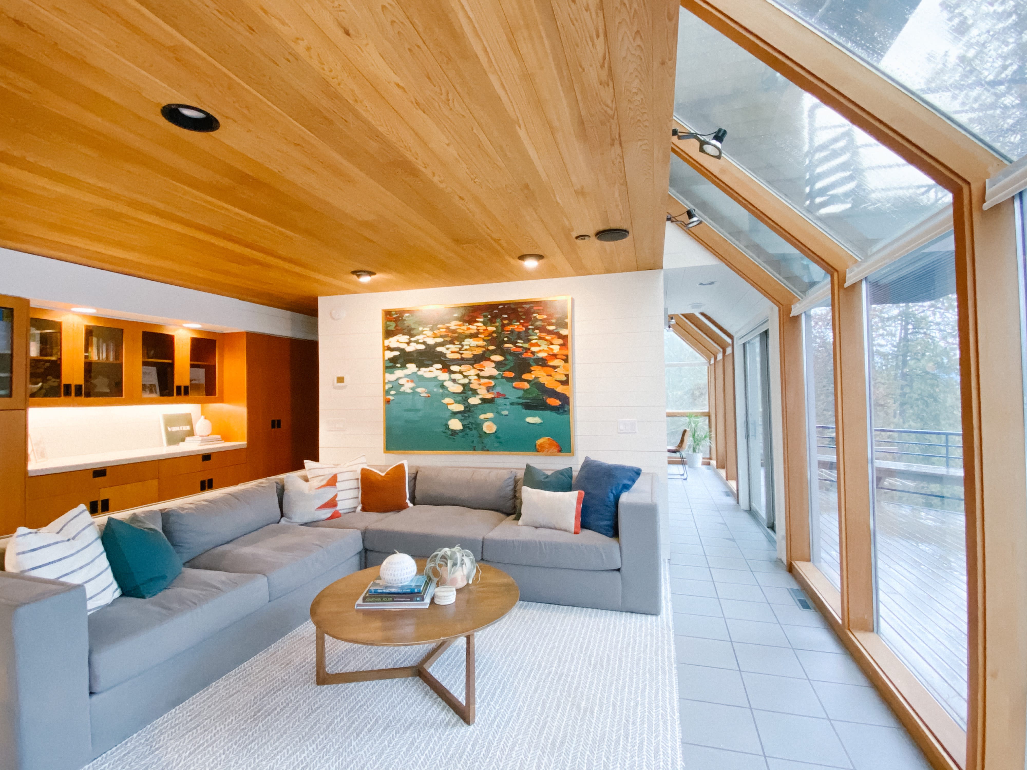 A cozy interior features a large window showcasing a scenic outdoor view while a sofa and dining table occupy the space.