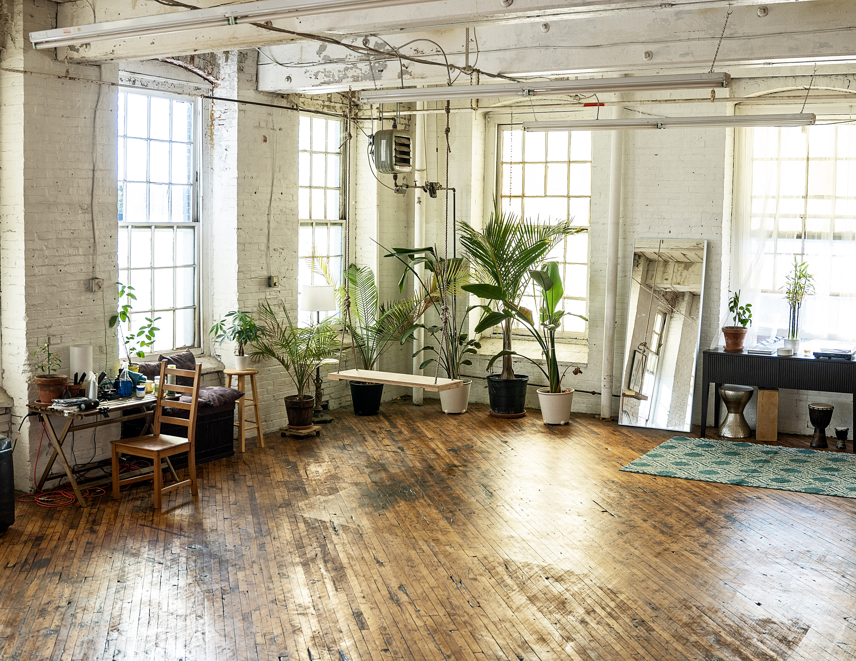A film crew sets up equipment in a studio adorned with a gallery of black and white portraits.