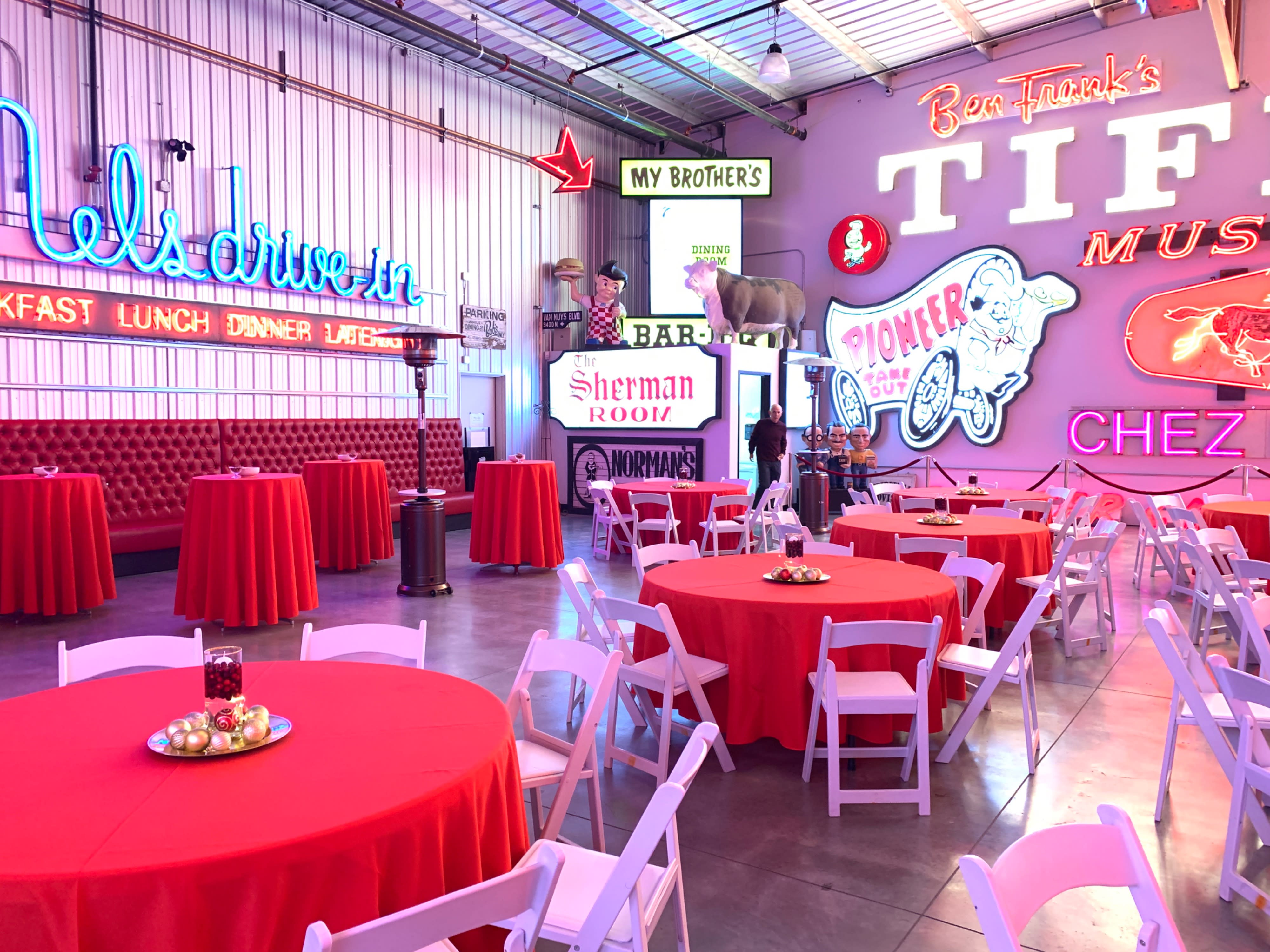 A group of people socializes and celebrates at a birthday party in a lively venue decorated with colorful balloons and signs.