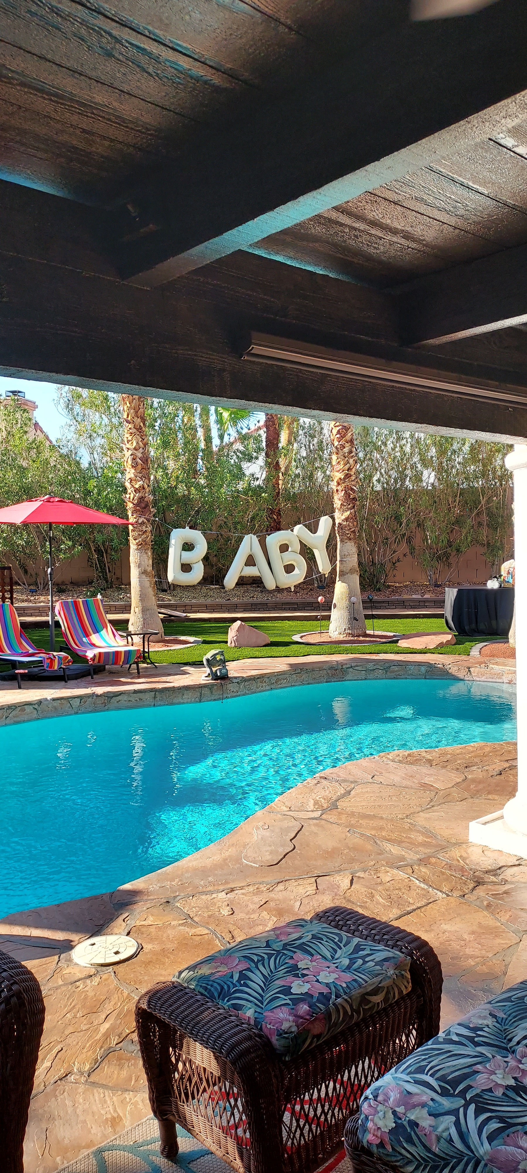 Two people enjoy a wedding reception by relaxing in a pool, one leaning on the edge while the other swims nearby.