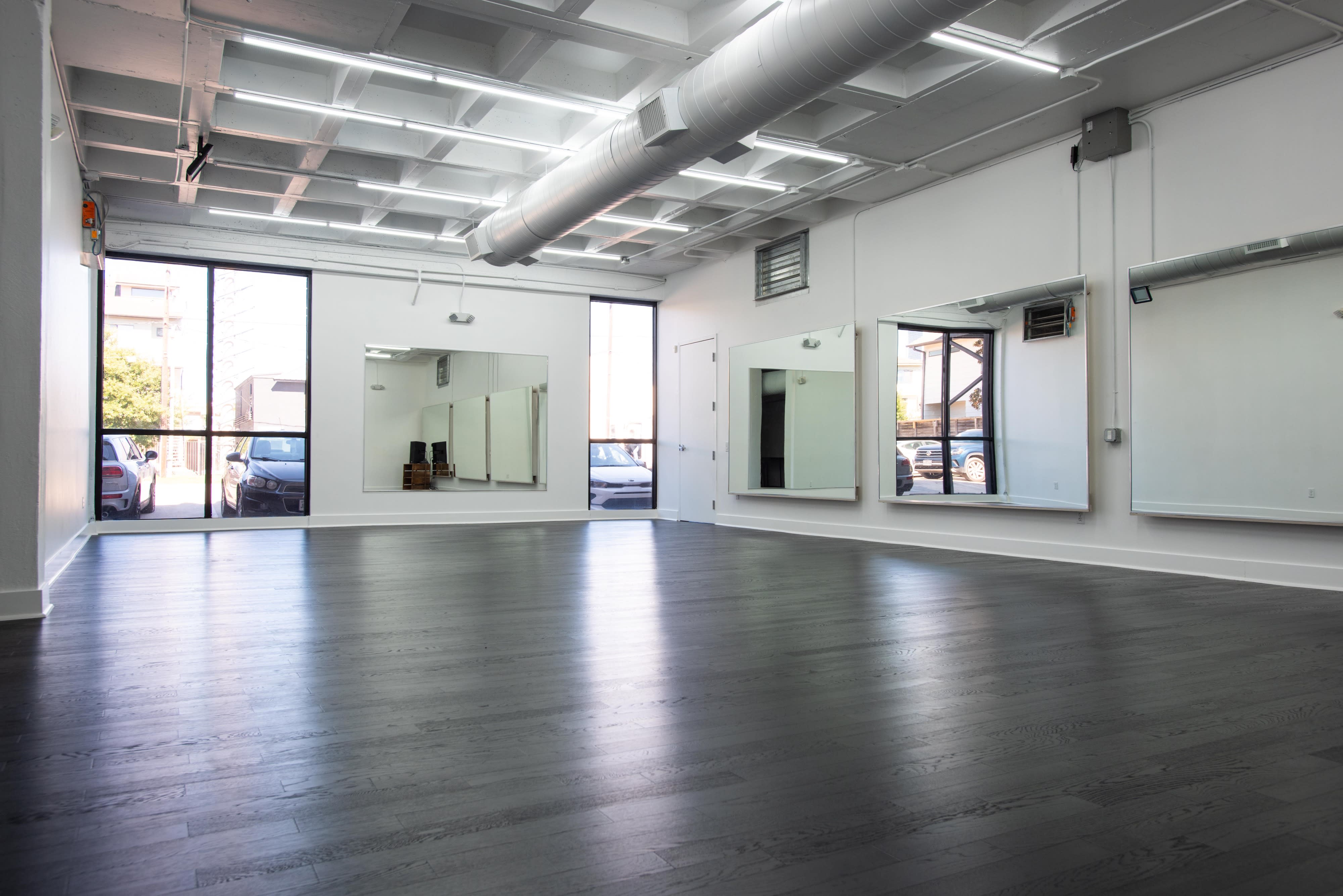 A group of people engages in various yoga poses on mats in a bright, spacious studio.