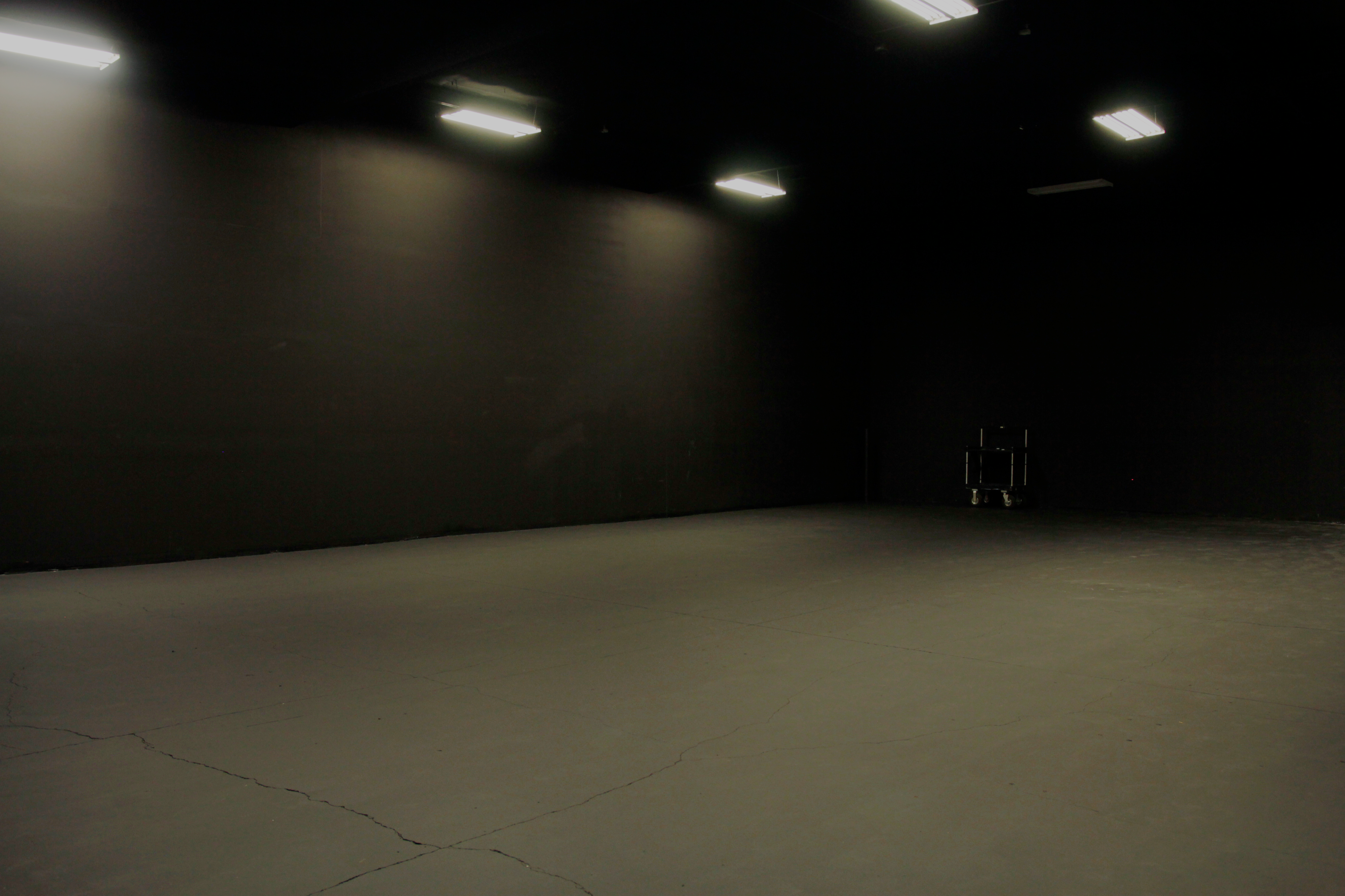 A cyclist takes a hydration break while holding a bike upside down in a studio setting.
