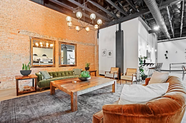 The image shows a dimly lit room set up for an engagement party, featuring a long table adorned with candles, flowers, and framed artwork on the walls.