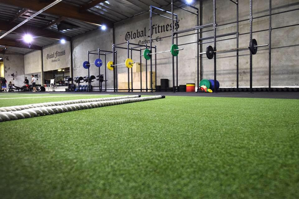 A man pushes a weighted sled across a gym floor during a workout.