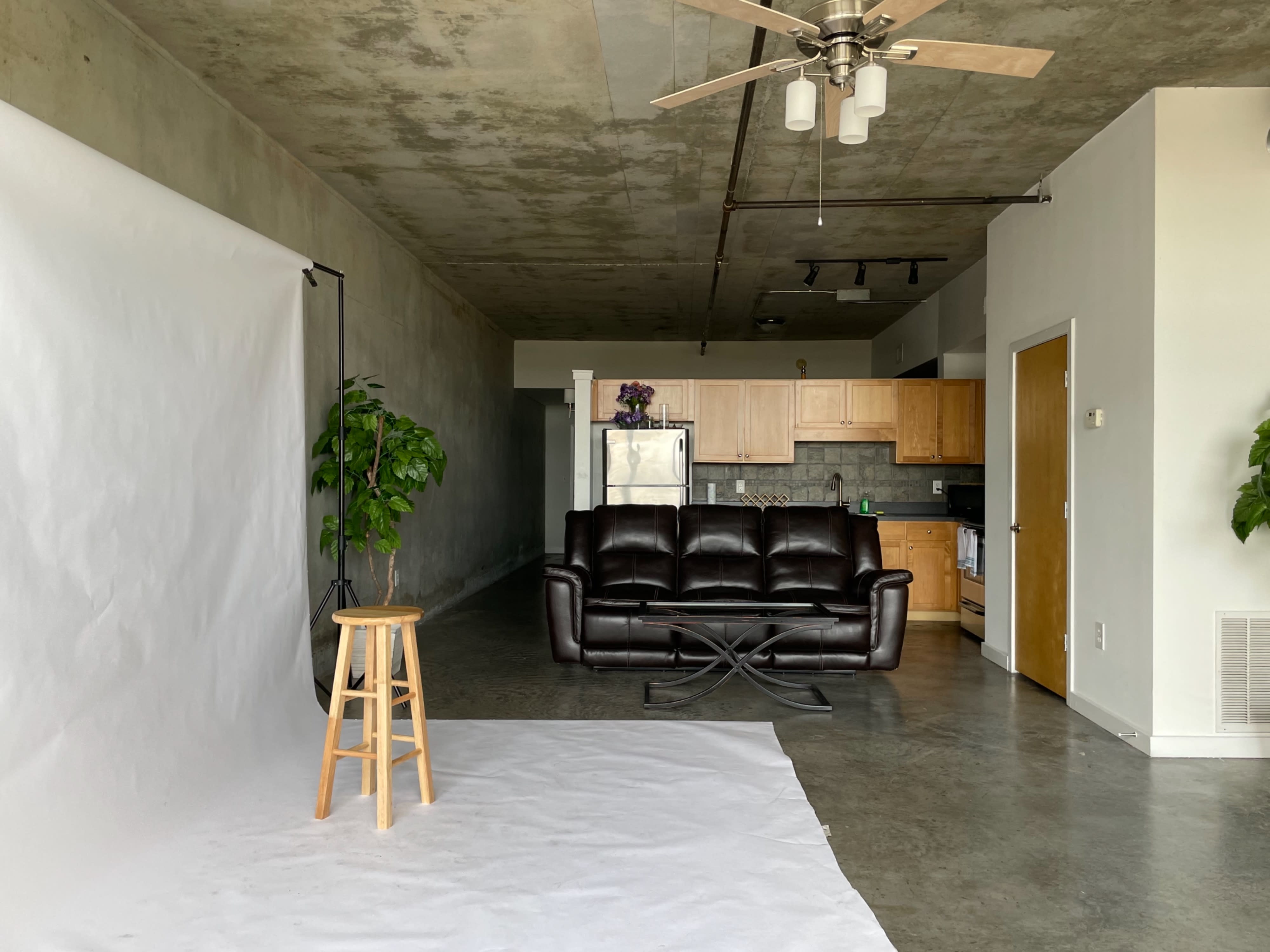 A photographer captures a model seated on a stool in a studio setting.