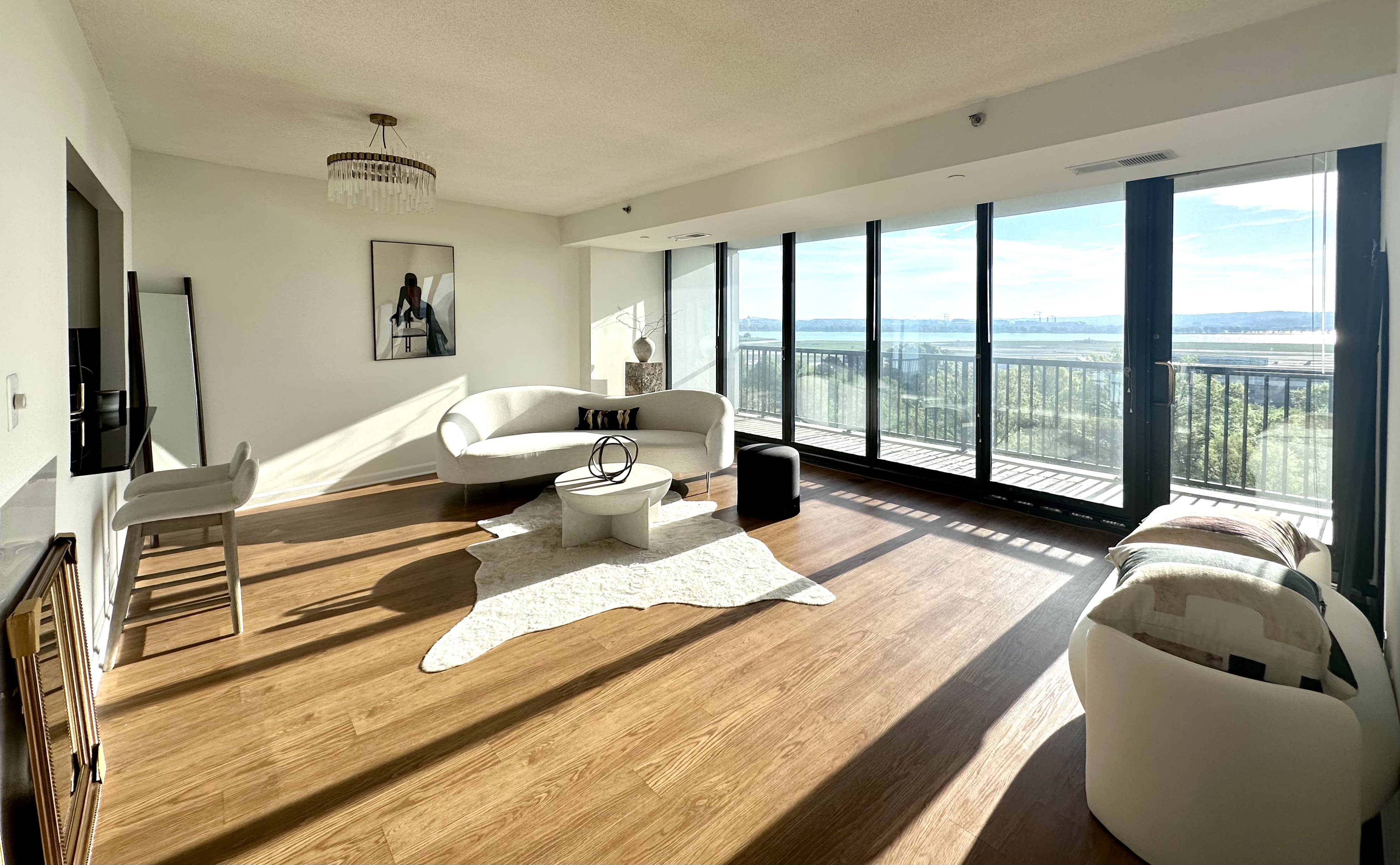 A model poses elegantly on a curved white sofa in a modern living room, striking a confident stance.