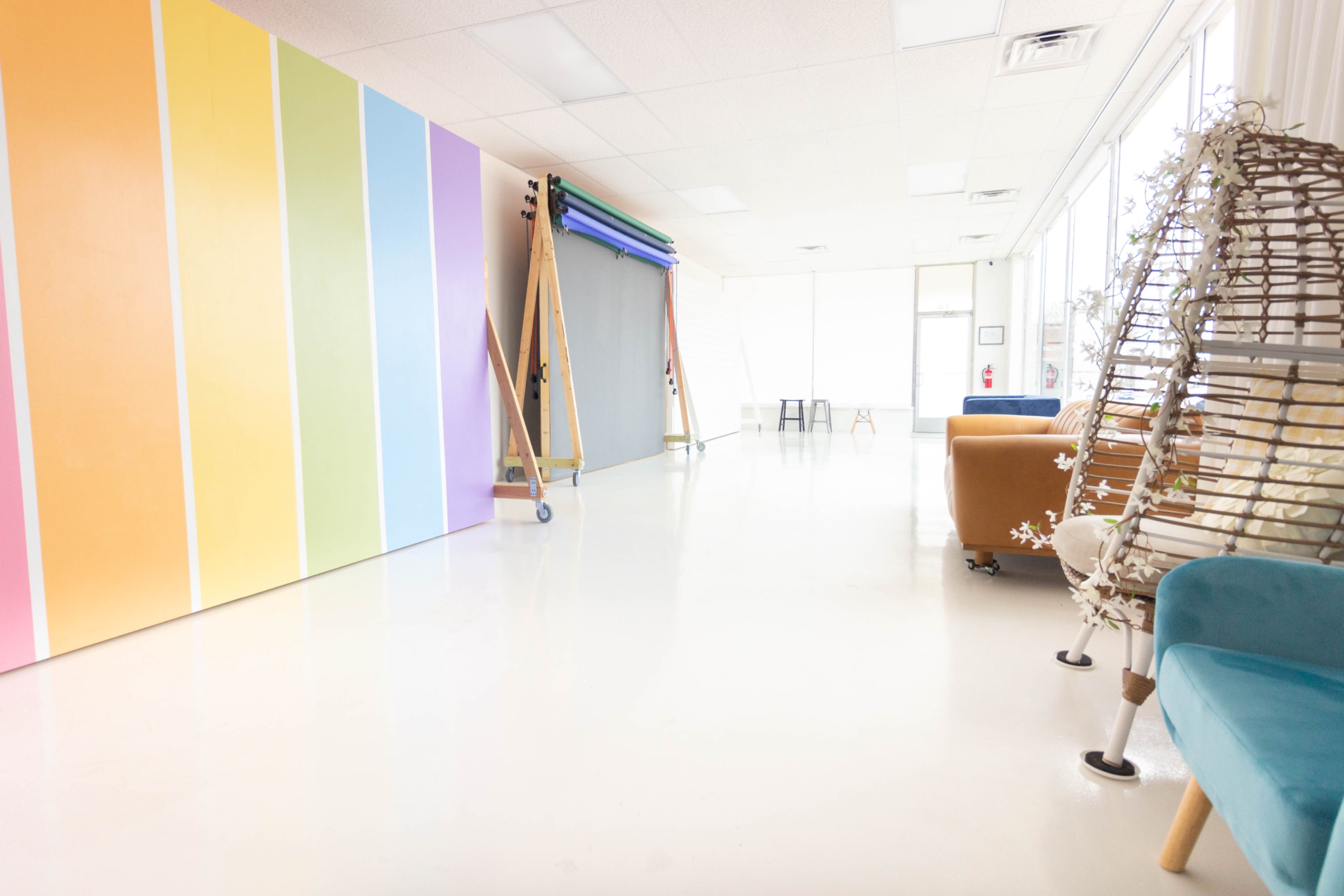 A couple sits on the floor, smiling and tossing photos into the air in a bright, minimalist studio.