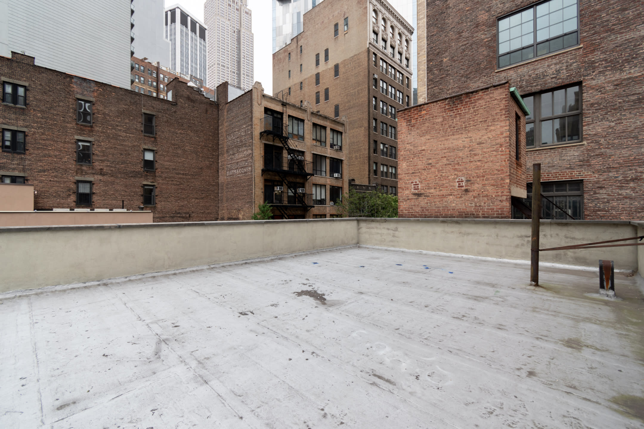 A smartphone on the ground captures a photoshoot of a person posing with a large sheet in front of a tall building.