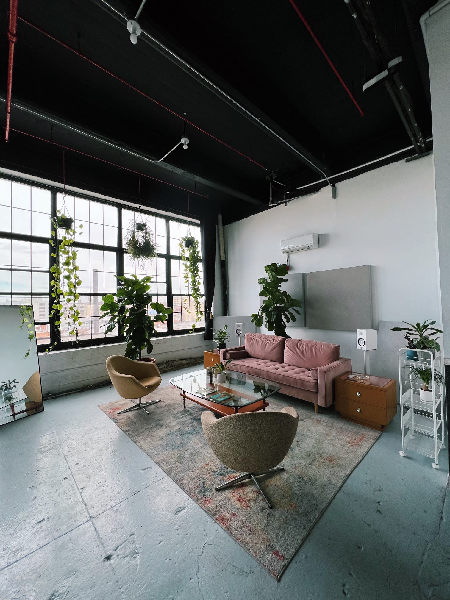 A musician plays a keyboard while being filmed in a stylish studio with large windows and plants.