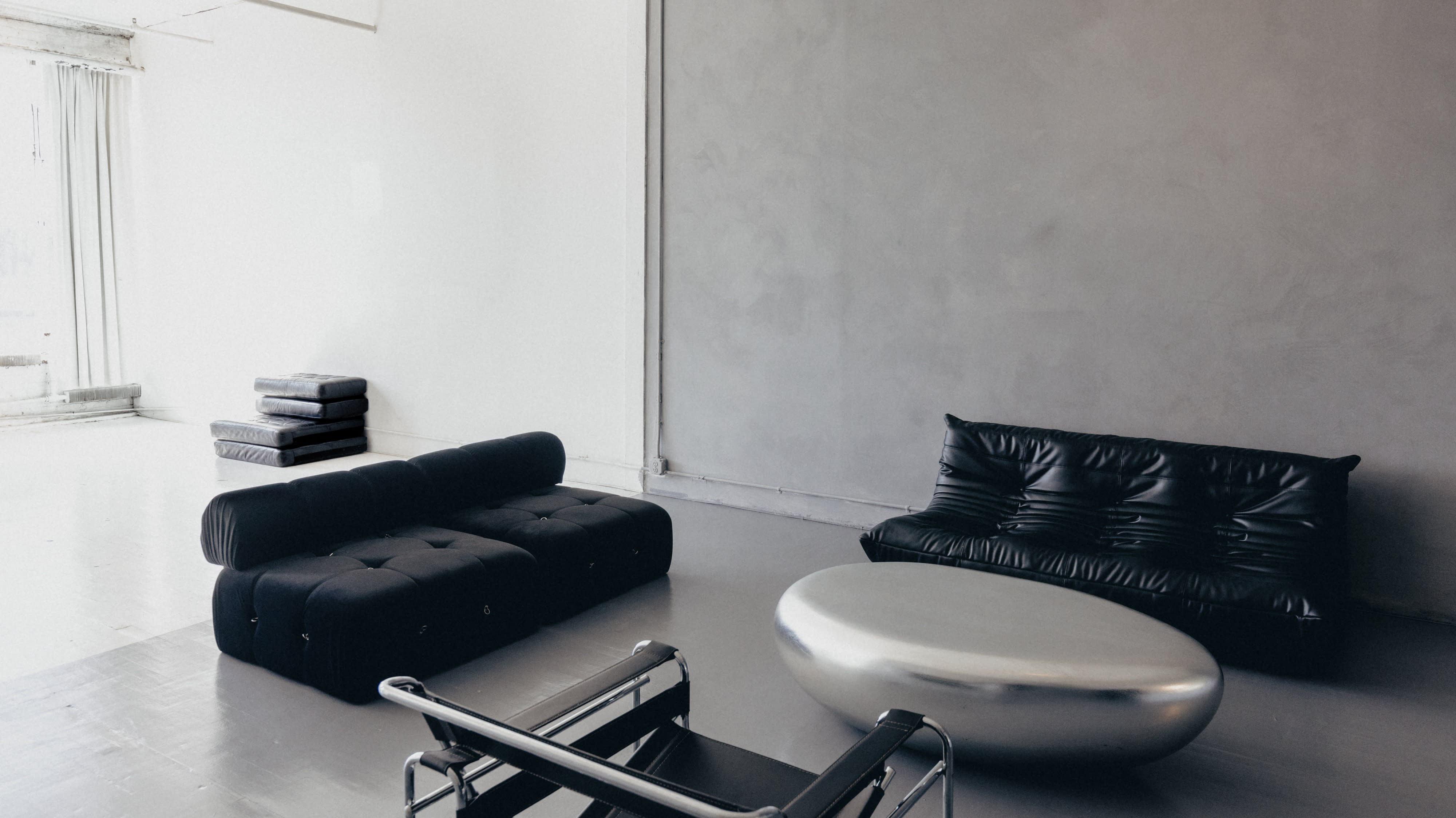 A photography studio setup features a white backdrop, a stool, and a large softbox light.