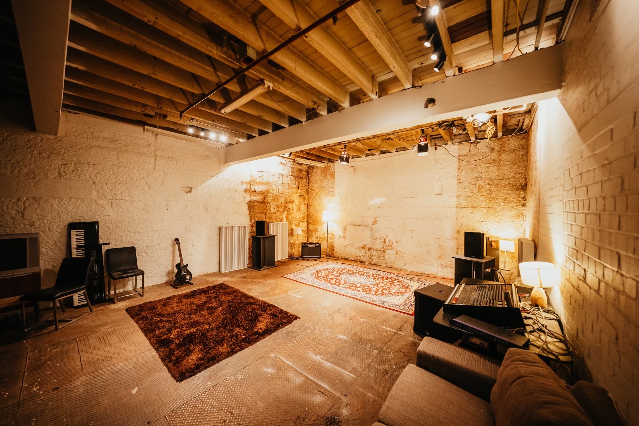 A band performs in a sparse, industrial space during a music video shoot.