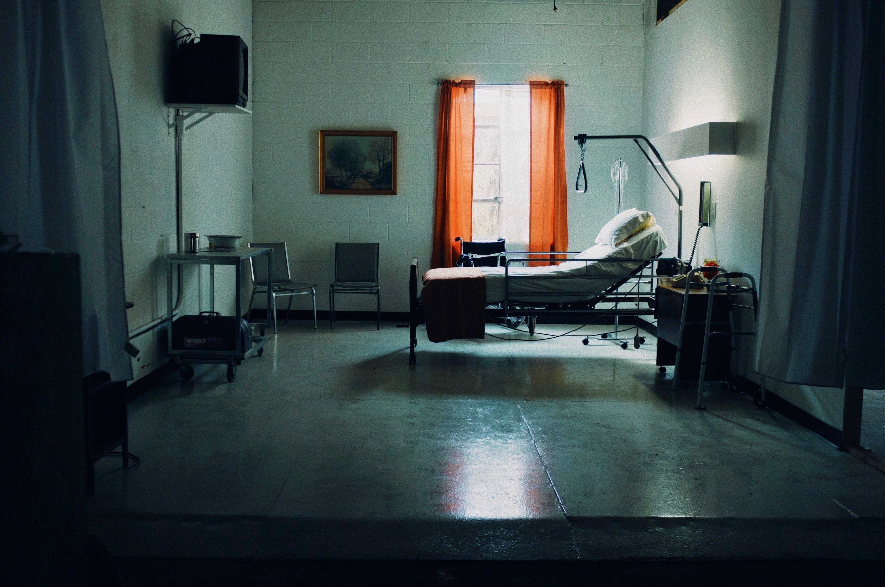 A man in a white suit plays a keyboard beside a woman lying in a hospital bed.