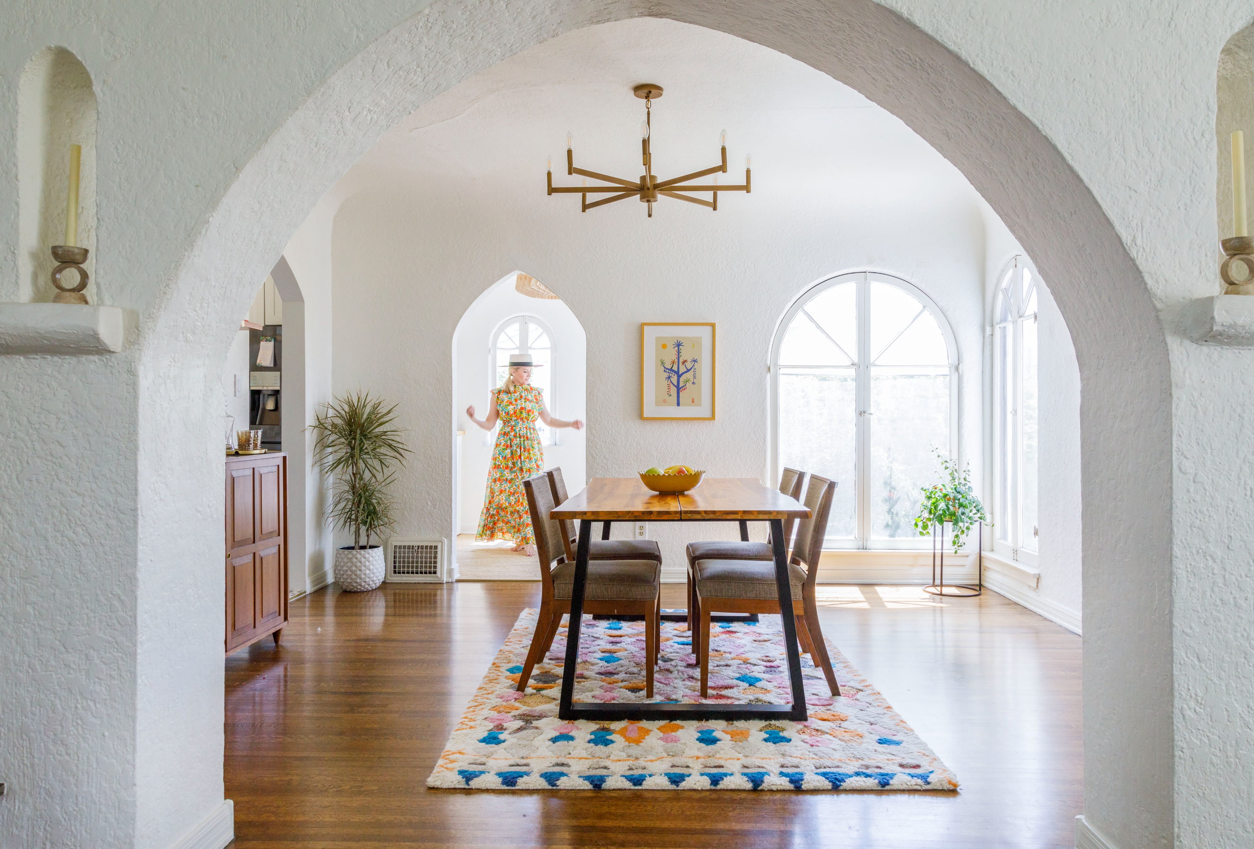 A photographer captures a model posing in a stylish outfit within a bright, well-decorated living room.