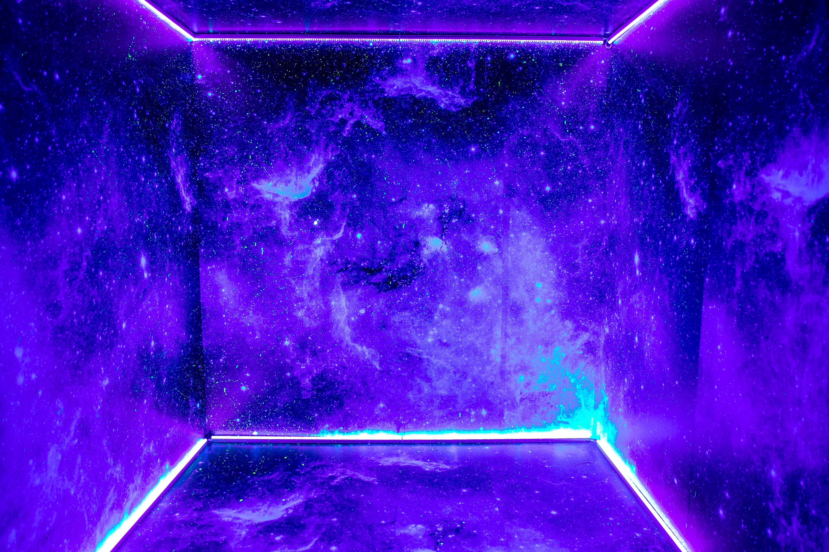 A person poses dramatically in a brightly lit blue room adorned with a starry backdrop.