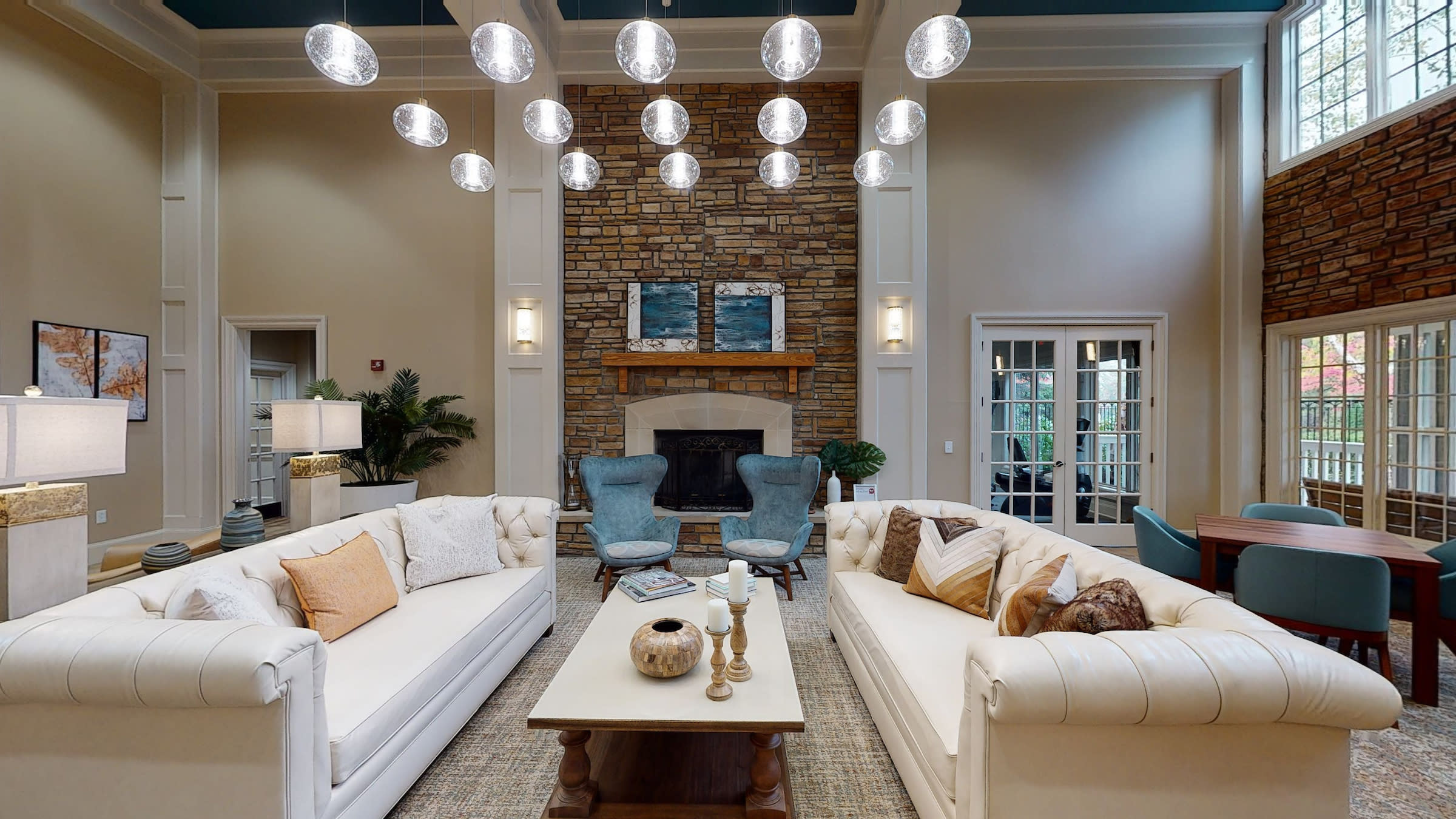 A tiered display of champagne coupes adorned with greenery stands on a table in a cozy living room setting.