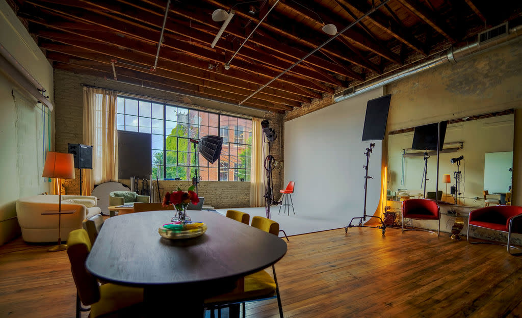 A group of photographers captures a model posing on a pedestal in a well-lit studio space.