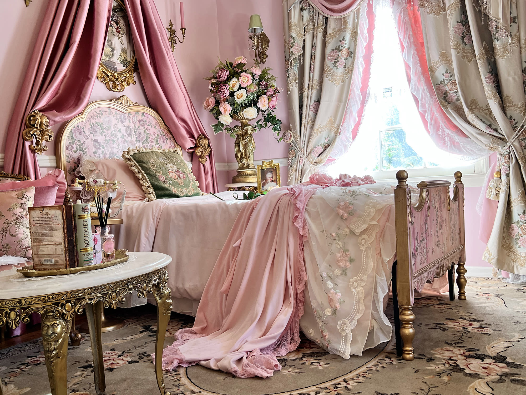 Two women are seated at a richly decorated table, engaged in lively conversation during a video shoot set in a vintage-inspired room.