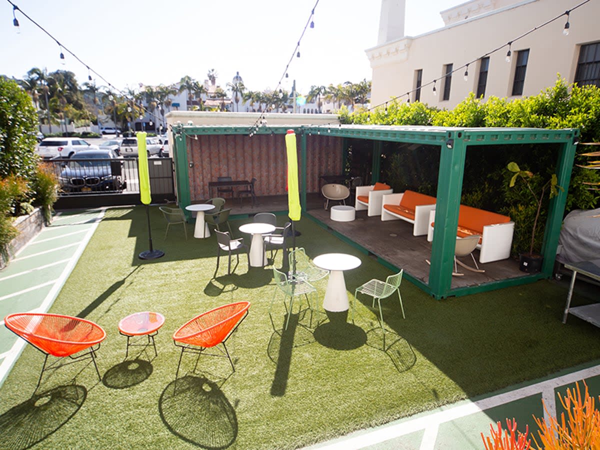Guests socialize and enjoy drinks at an outdoor banquet event adorned with string lights.